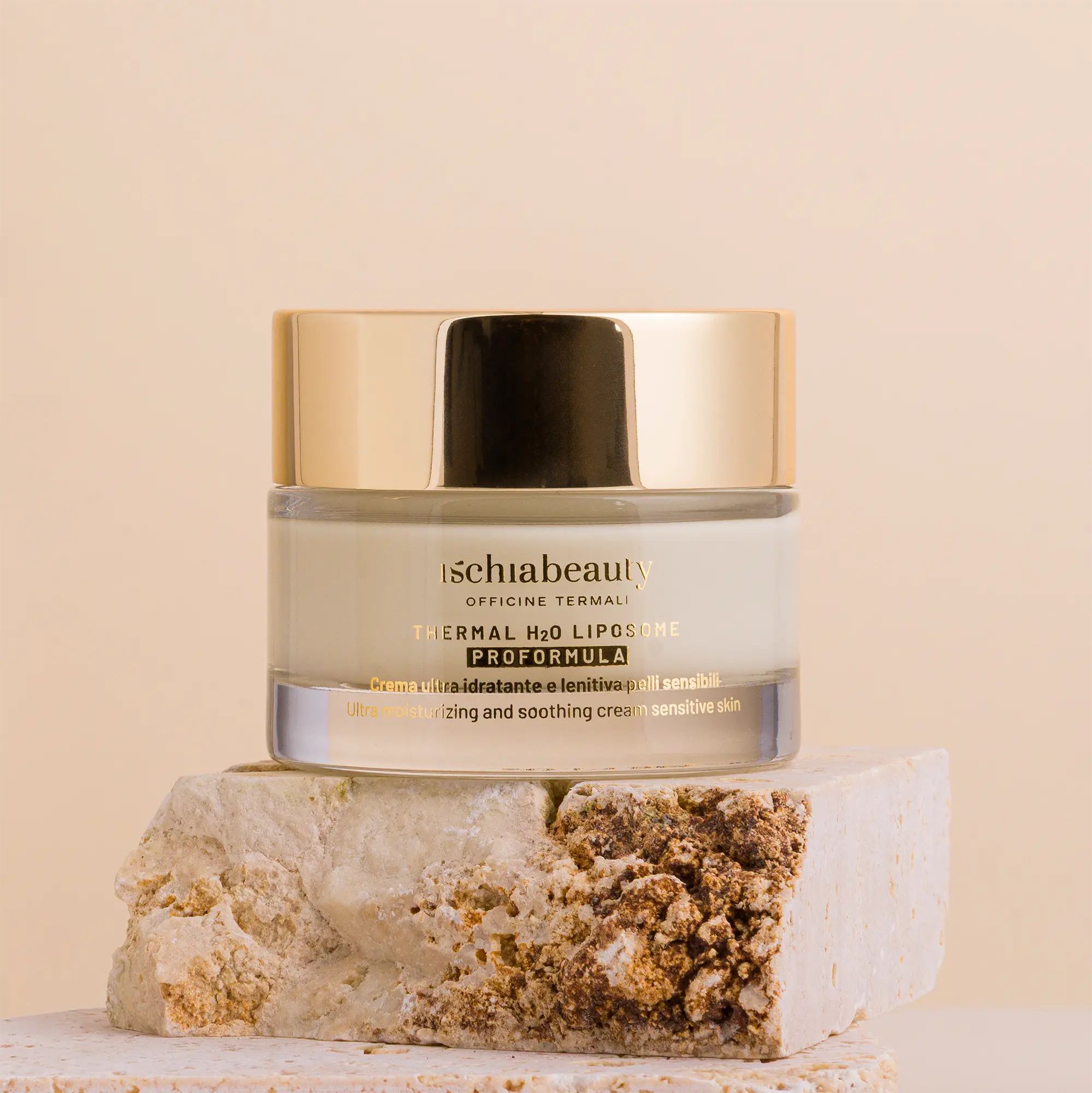Creme-Behälter mit goldenem Deckel. Text: ischiabeauty, Thermal H2O Liposome, Proformula. Auf Stein platziert.