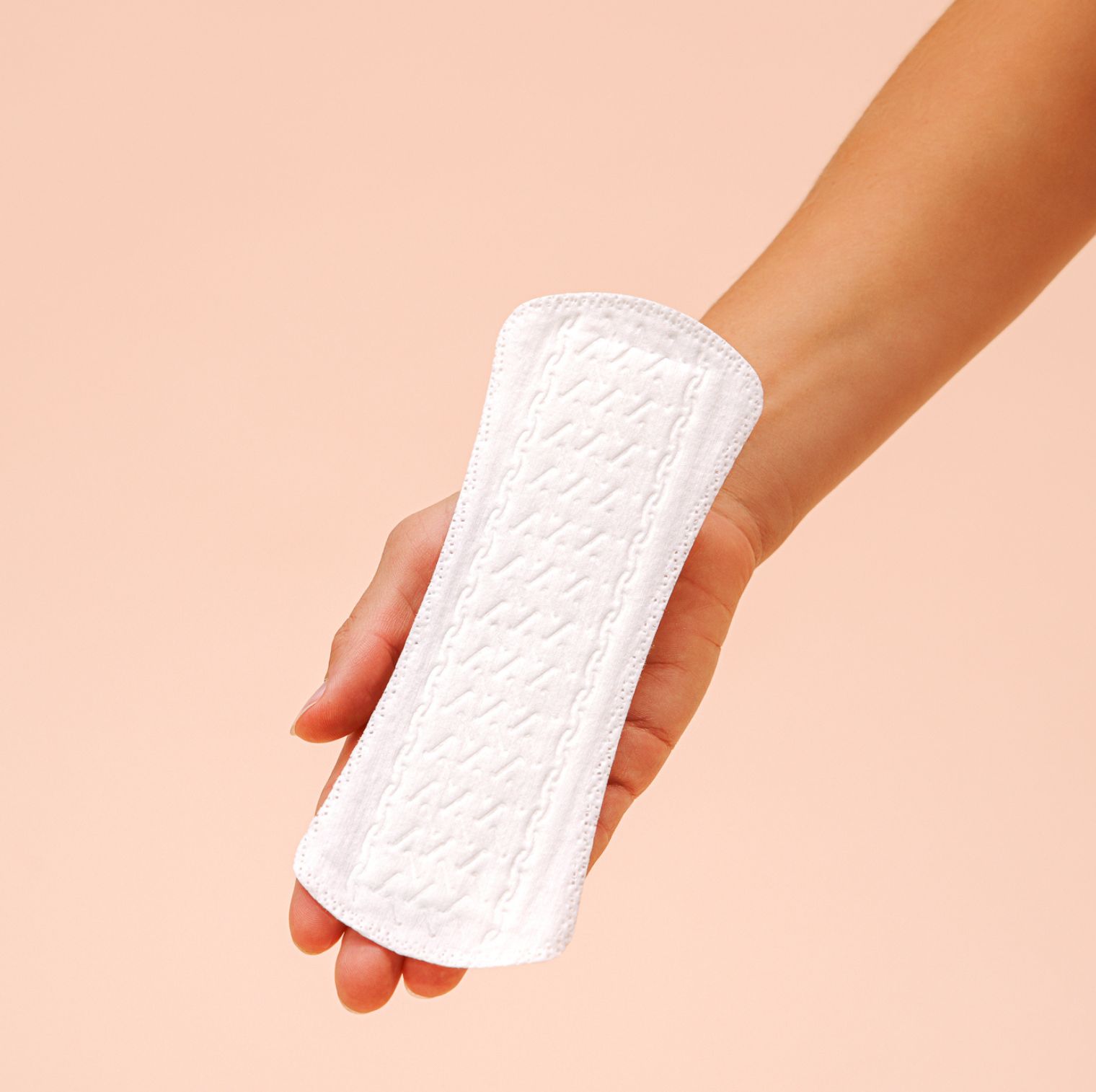 Weiße Slipeinlage mit geprägter Oberfläche, gehalten in einer Hand. Rosa Hintergrund.