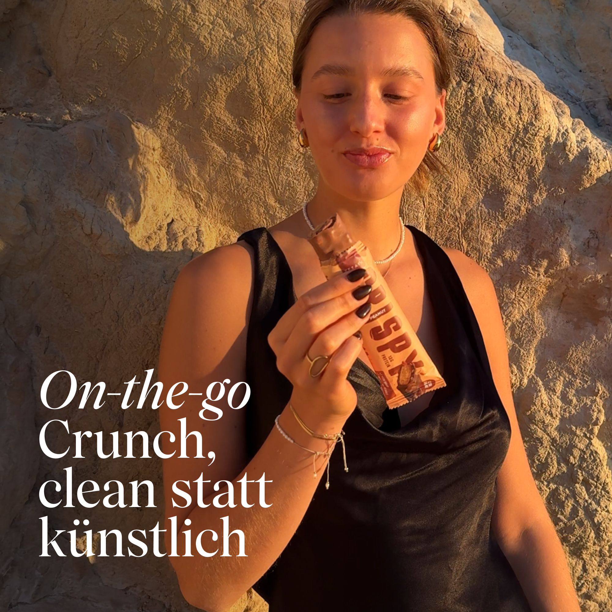 Frau hält Proteinriegel. Aufschrift "CRISPY". Text: "On-the-go Crunch, clean statt künstlich".