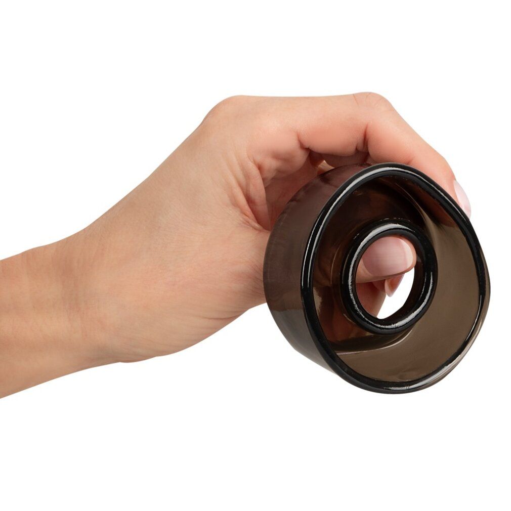 Hand hält dunkelbraune Ersatzmanschette. Zylindrische Form mit innerem Ring. Transparentes Material.