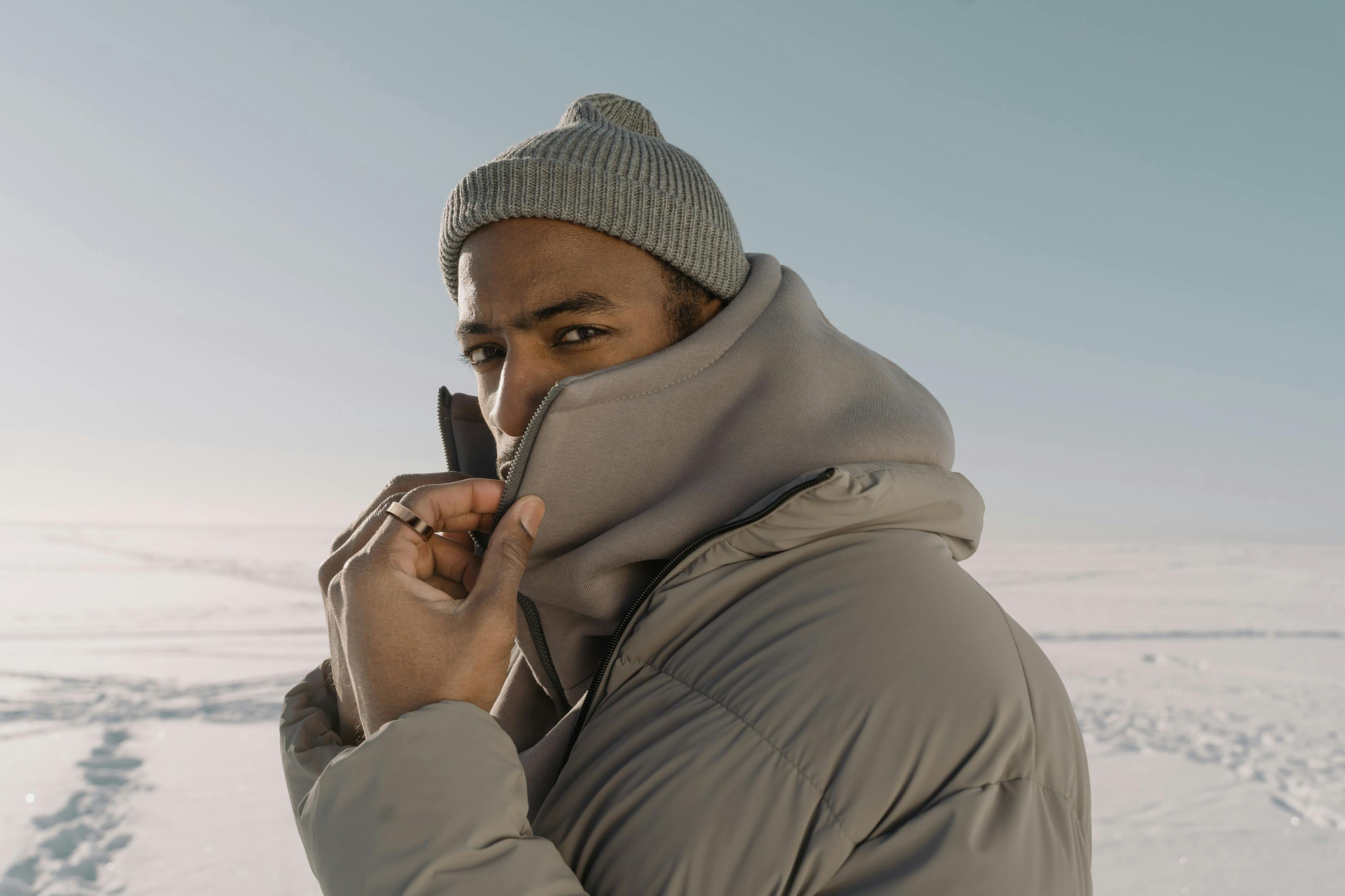 Mann im Winter mit grauer Jacke und Mütze. Goldfarbener Ring am Finger.
