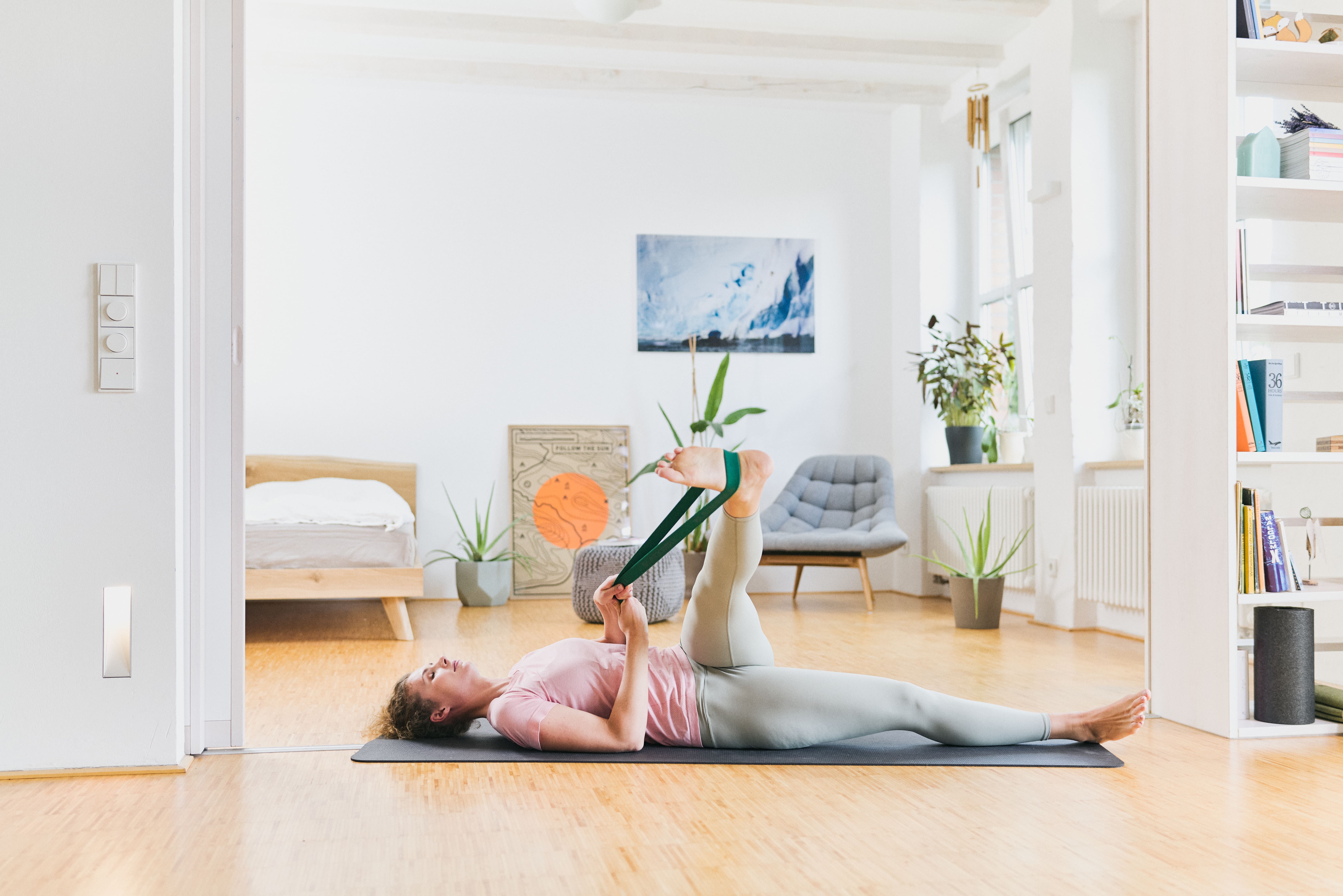 Frau liegt auf einer Matte und dehnt sich mit einem grünen BLACKROLL Loop Band.