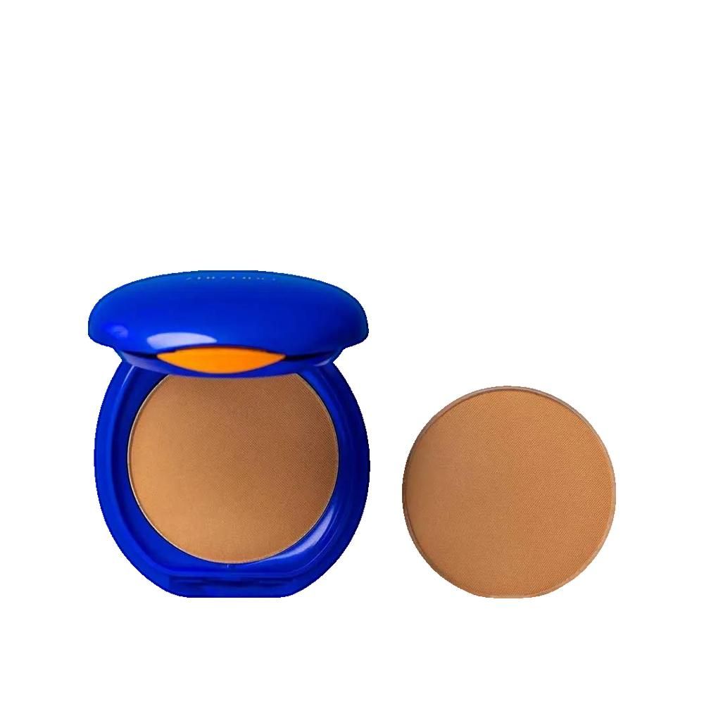 Kompaktpuder mit blauem Deckel, geöffnet. Daneben ein runder Puder. Helle Hautfarbe.