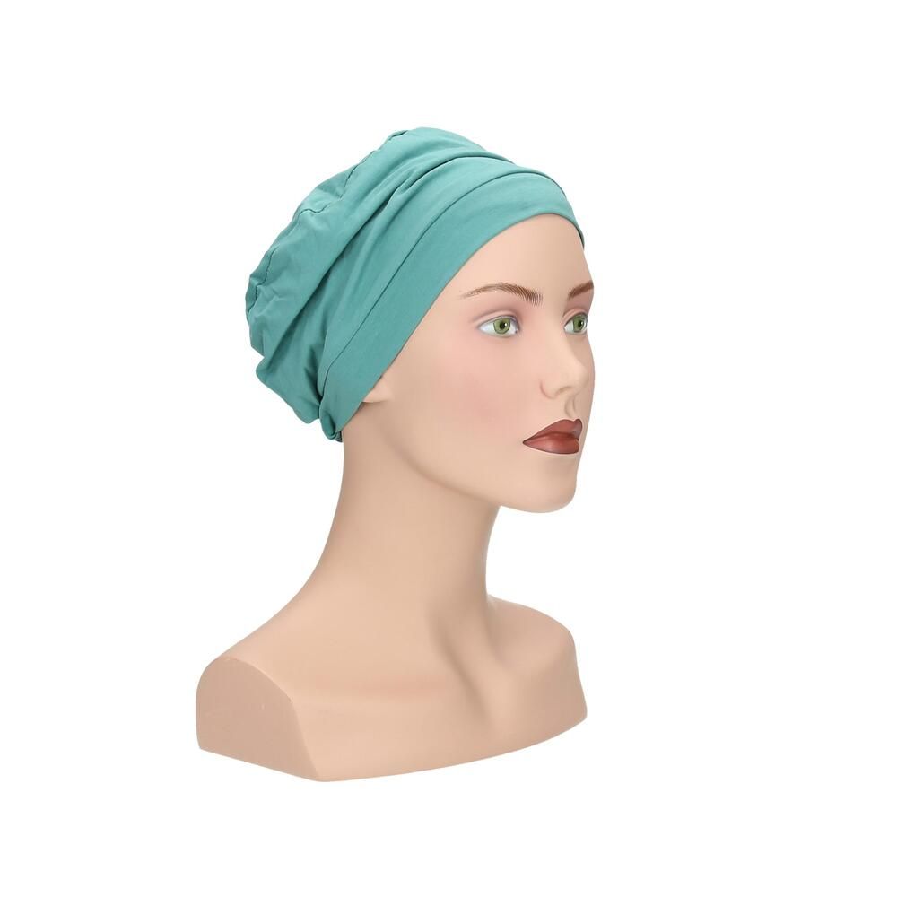 Türkisfarbener Turban auf Schaufensterpuppe. Frontansicht. Gerüschte Details, glatter Stoff.