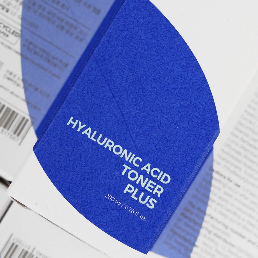 Blauer Karton mit weißer Schrift: Hyaluronic Acid Toner Plus. 200 ml/6.76 fl. oz. Detailansicht.