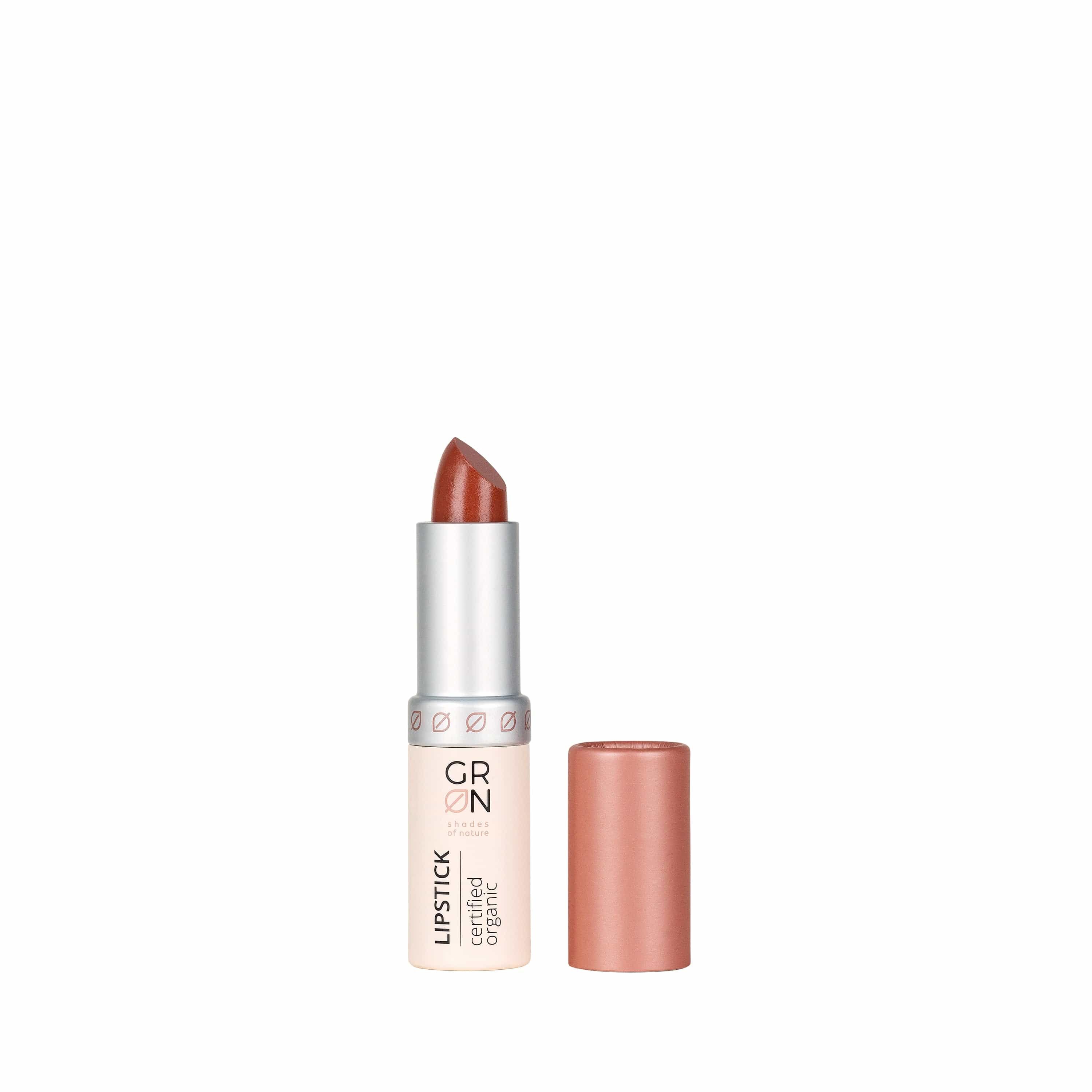 Lippenstift, teilweise geöffnet. Silberfarbener Stift mit braunem Lippenstift. Deckel daneben. Aufschrift: GRN, Lipstick, certified organic.