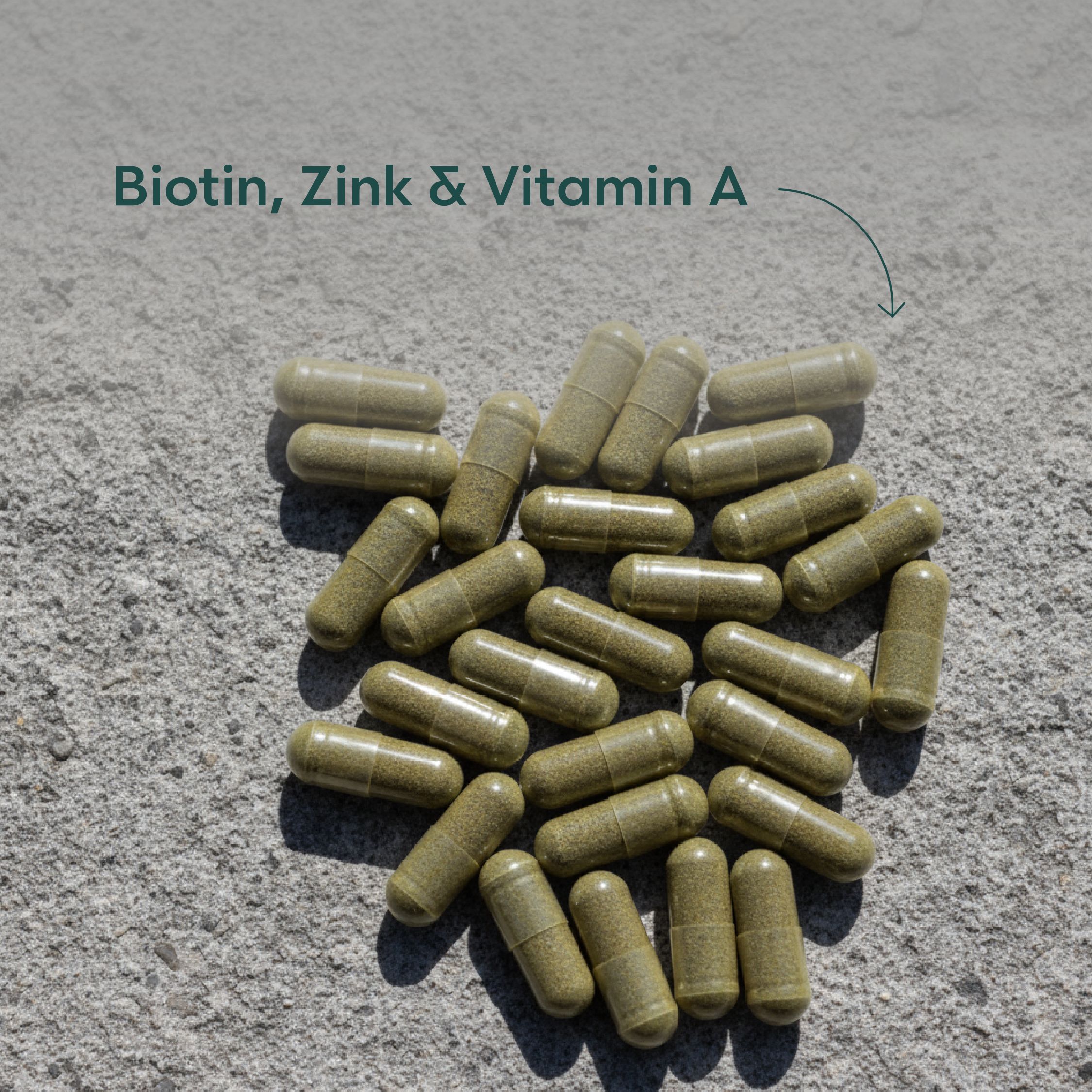 Haufen grüner Kapseln auf grauem Untergrund. Aufschrift: Biotin, Zink & Vitamin A.