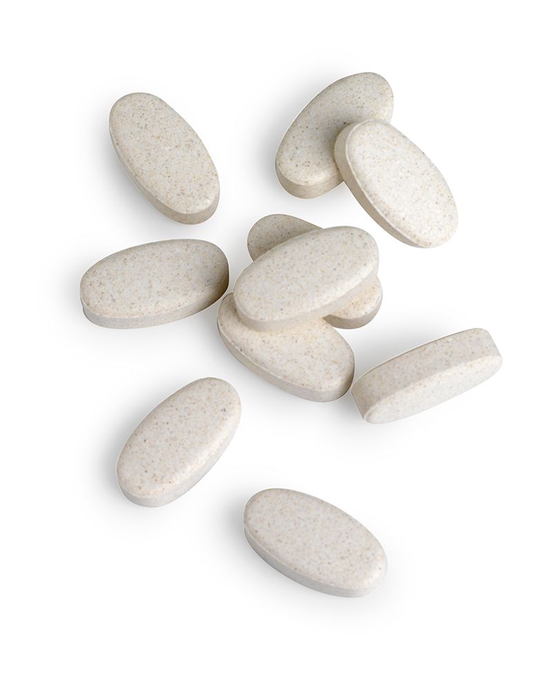 Zehn ovale, beige Tabletten. Einzeln und in einer Gruppe angeordnet.