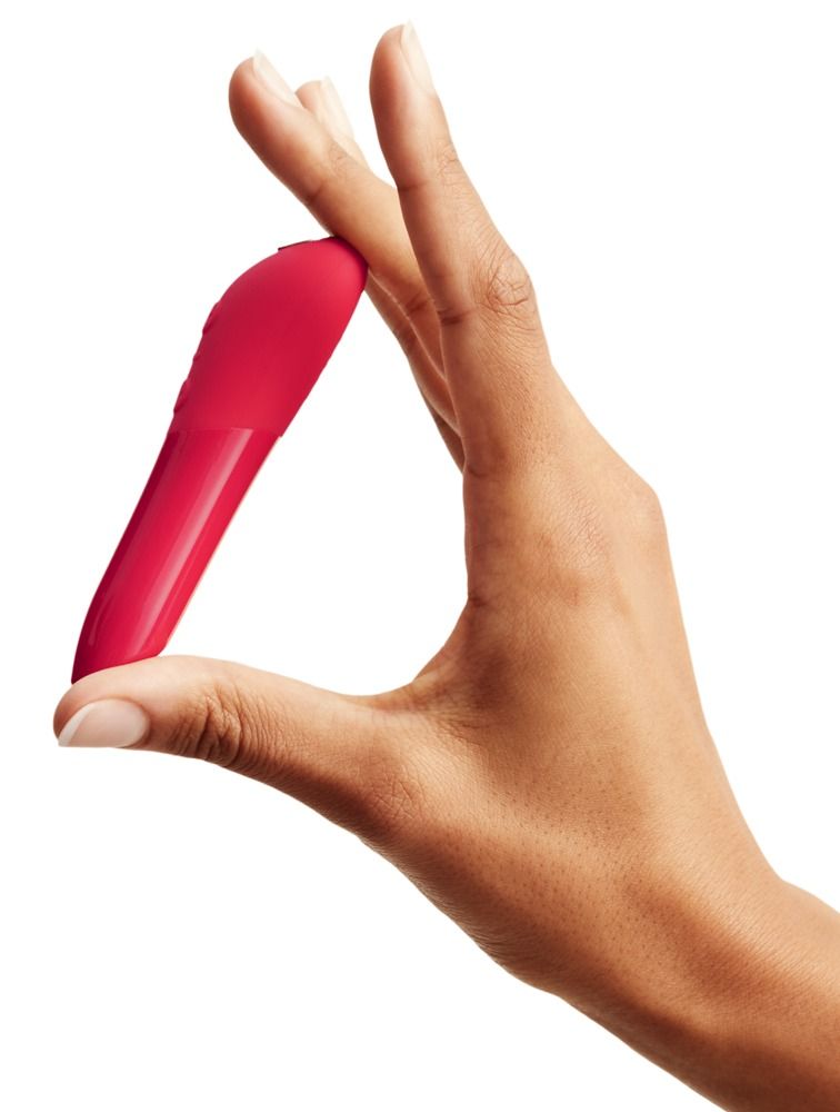 Roter Vibrator wird zwischen zwei Fingern gehalten. Weißer Hintergrund.