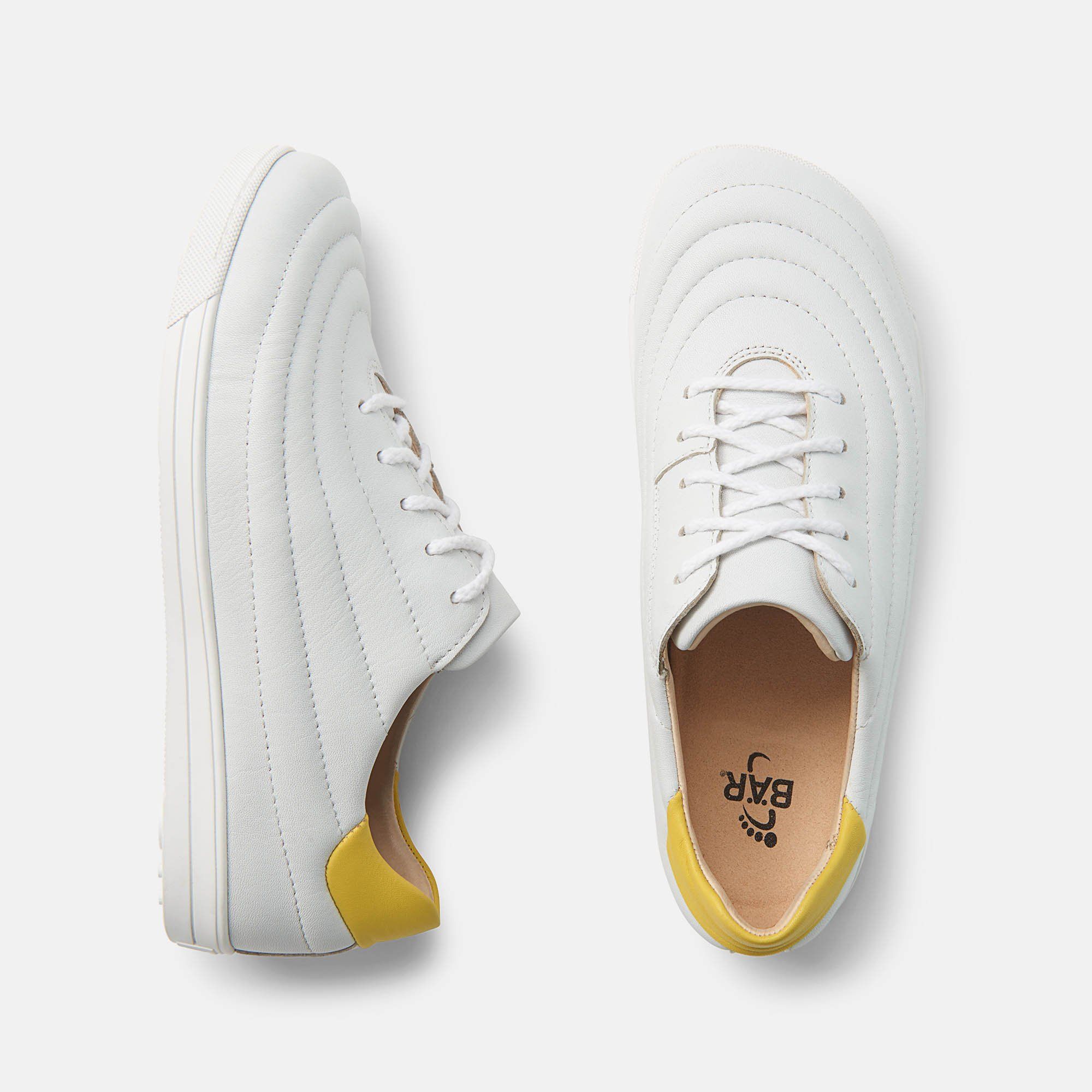 Zwei weiße Schuhe. Gelbe Fersenkappen. Gepolstertes Design. Flache Sohen. BÄR Logo.
