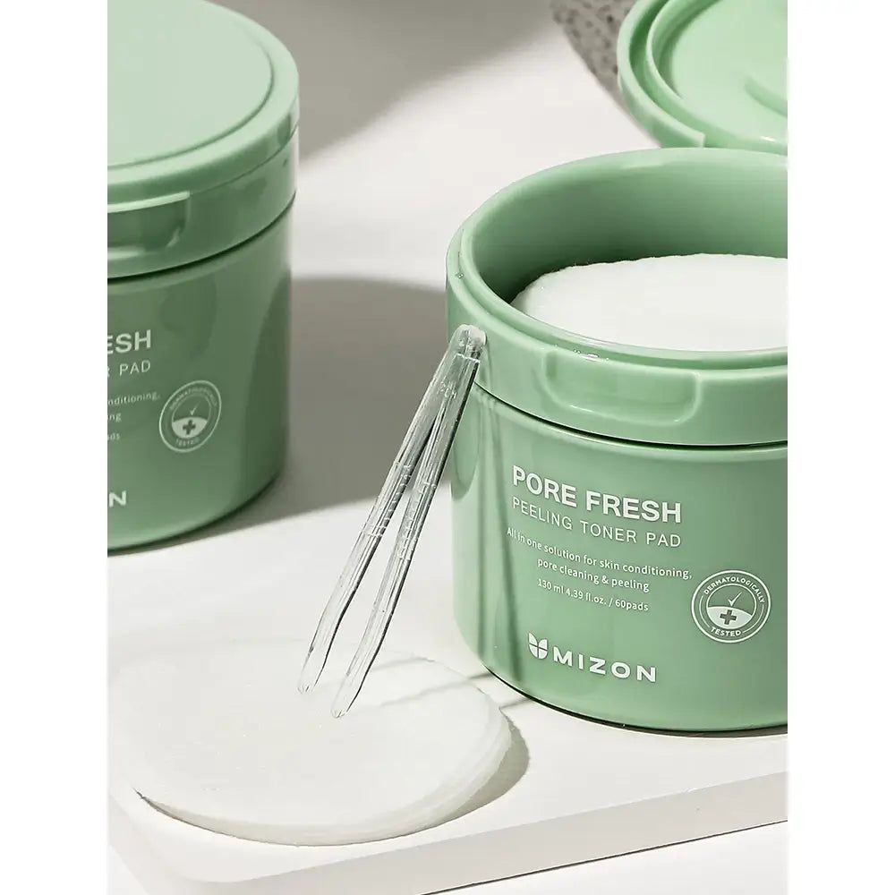 Grüner Behälter mit Peeling-Toner-Pads und Pinzette.