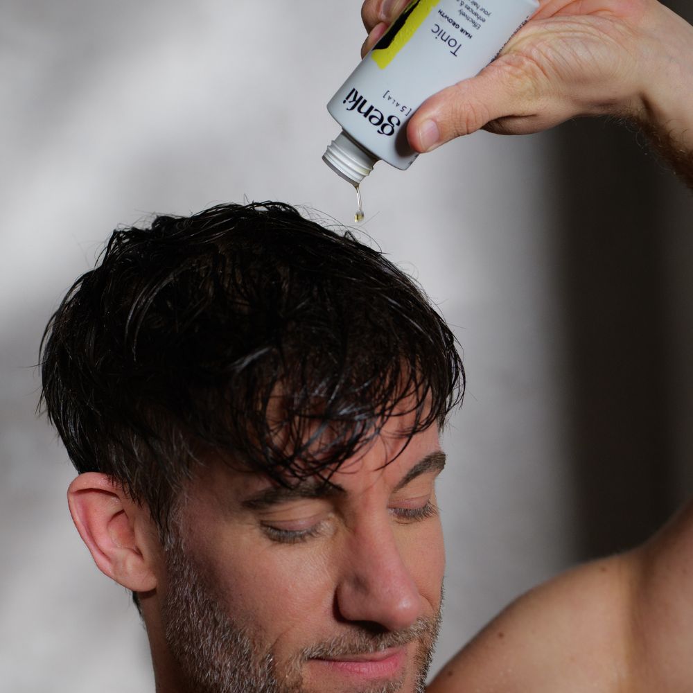Person gießt Genki Tonic auf Haare. Weiße Flasche mit schwarzem Deckel. Gelber Akzent. Schriftzug: Genki, Tonic.
