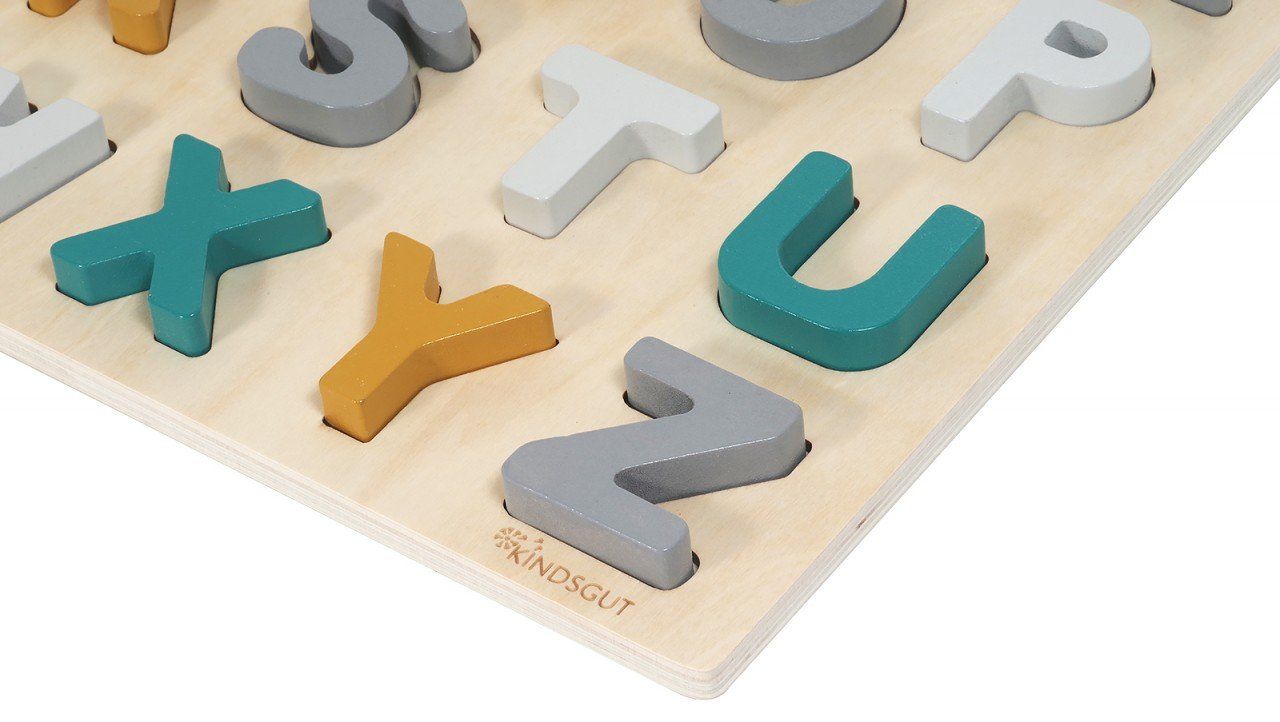 Nahaufnahme eines Holzpuzzles mit Buchstaben. Buchstaben in verschiedenen Farben. Der Markenname Kindsgut ist sichtbar.