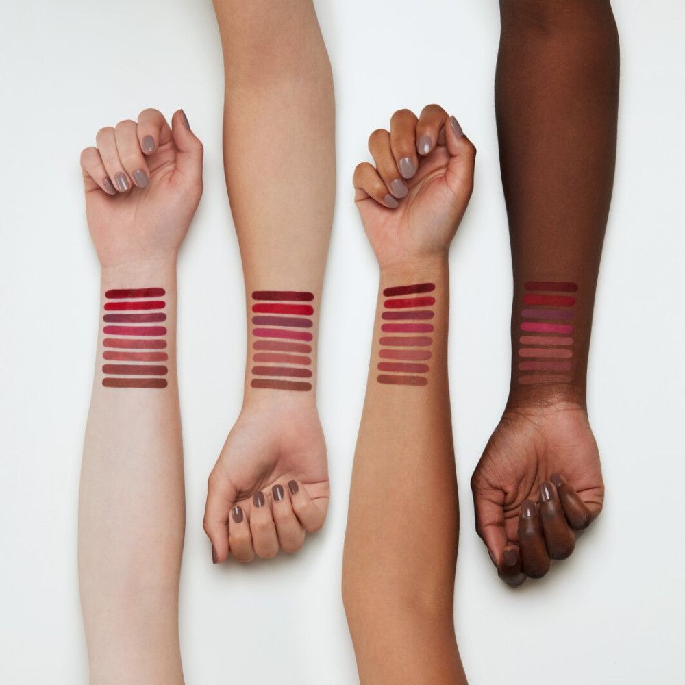 Vier Arme mit Lippenstiftfarben auf der Haut. Verschiedene Hauttöne. Mehrere Farbtöne.