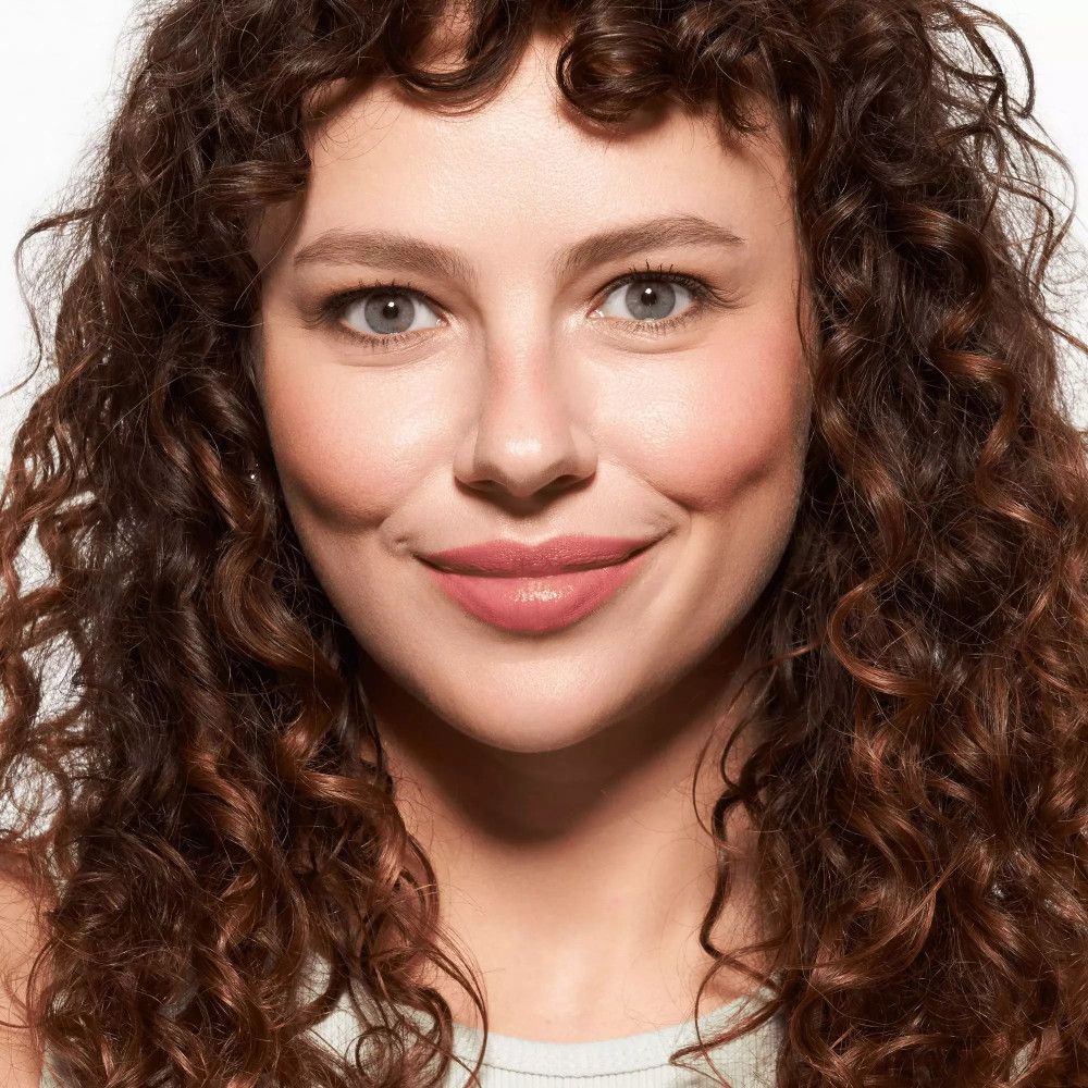 Porträt einer Frau mit Locken. Aufgetragenes Rouge auf den Wangen. Natürlicher Teint.