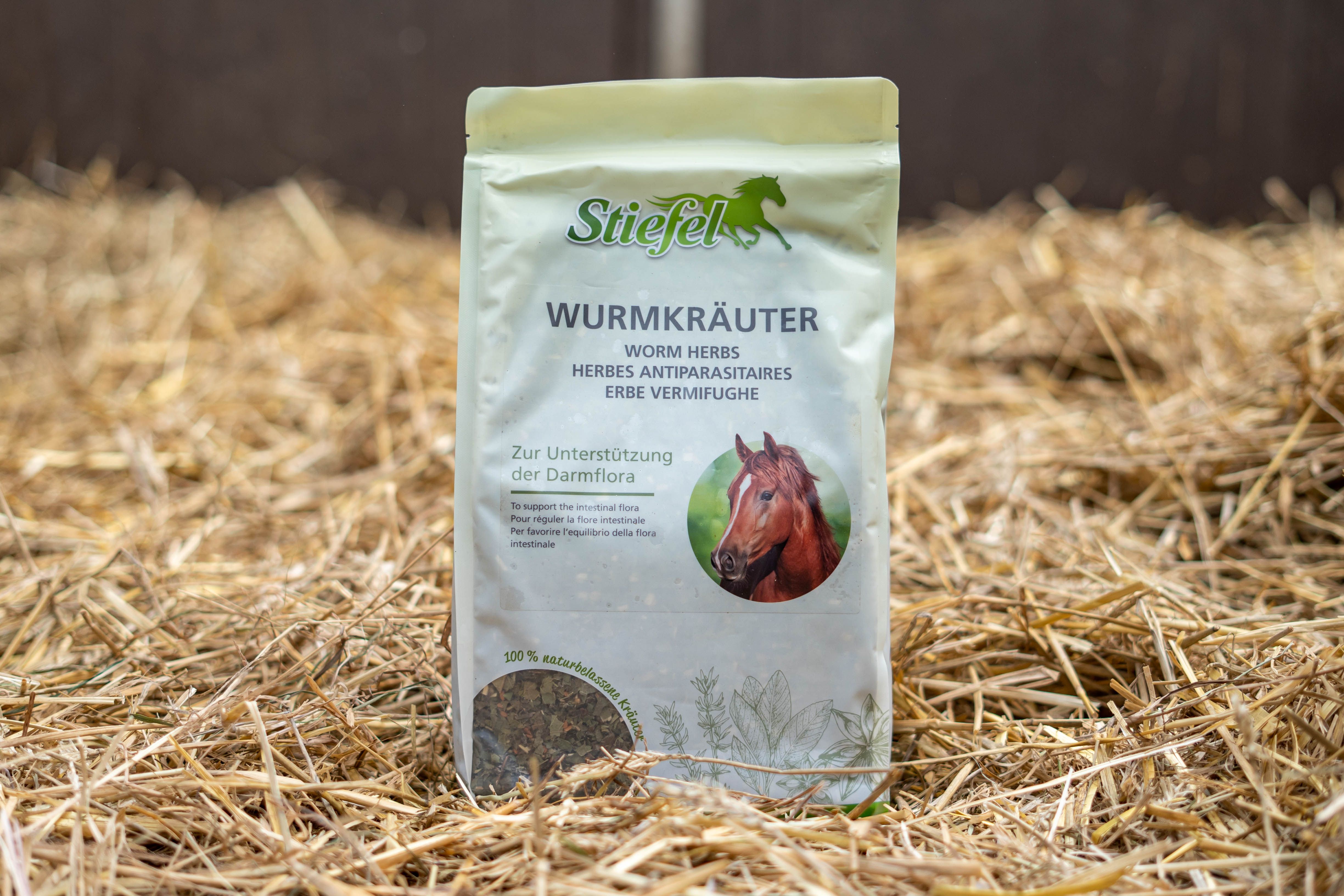 Beutel Stiefel Wurmkräuter auf Stroh. Aufschrift: Wurmkräuter. Abbildung eines Pferdes. Hintergrund aus Stroh.