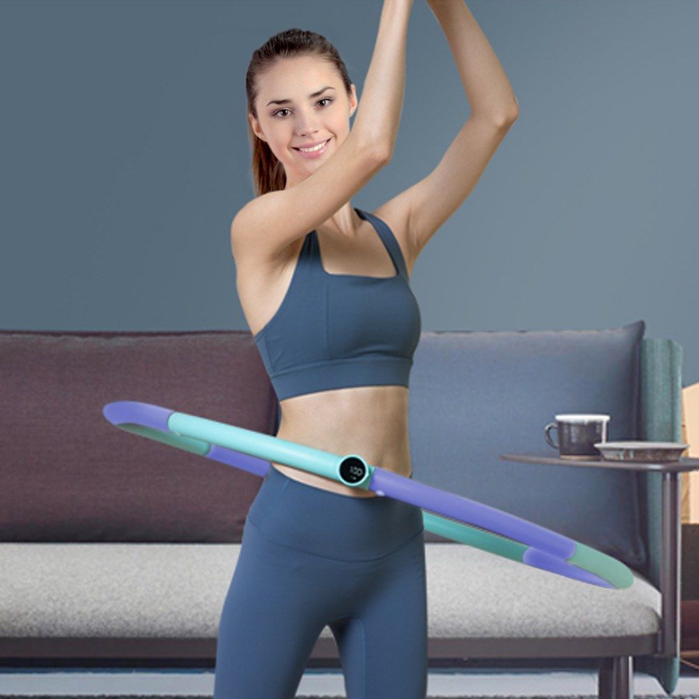 Frau mit blau-violettem Hula-Hoop-Reifen, der um ihre Taille liegt. Digitale Anzeige sichtbar.