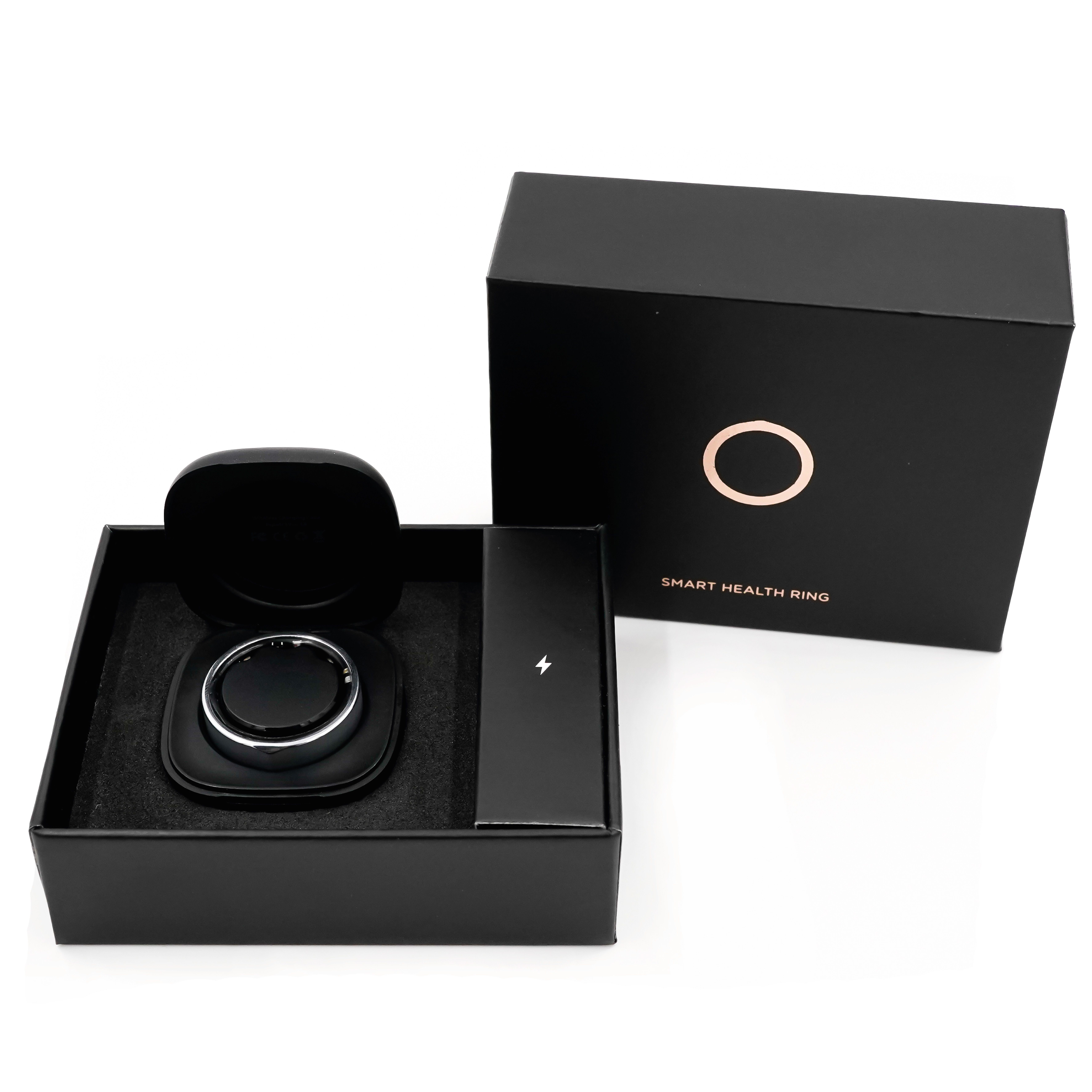 Schwarze Verpackung mit Ring und Ladezubehör. Ring in schwarzer Halterung. Aufschrift: Smart Health Ring.