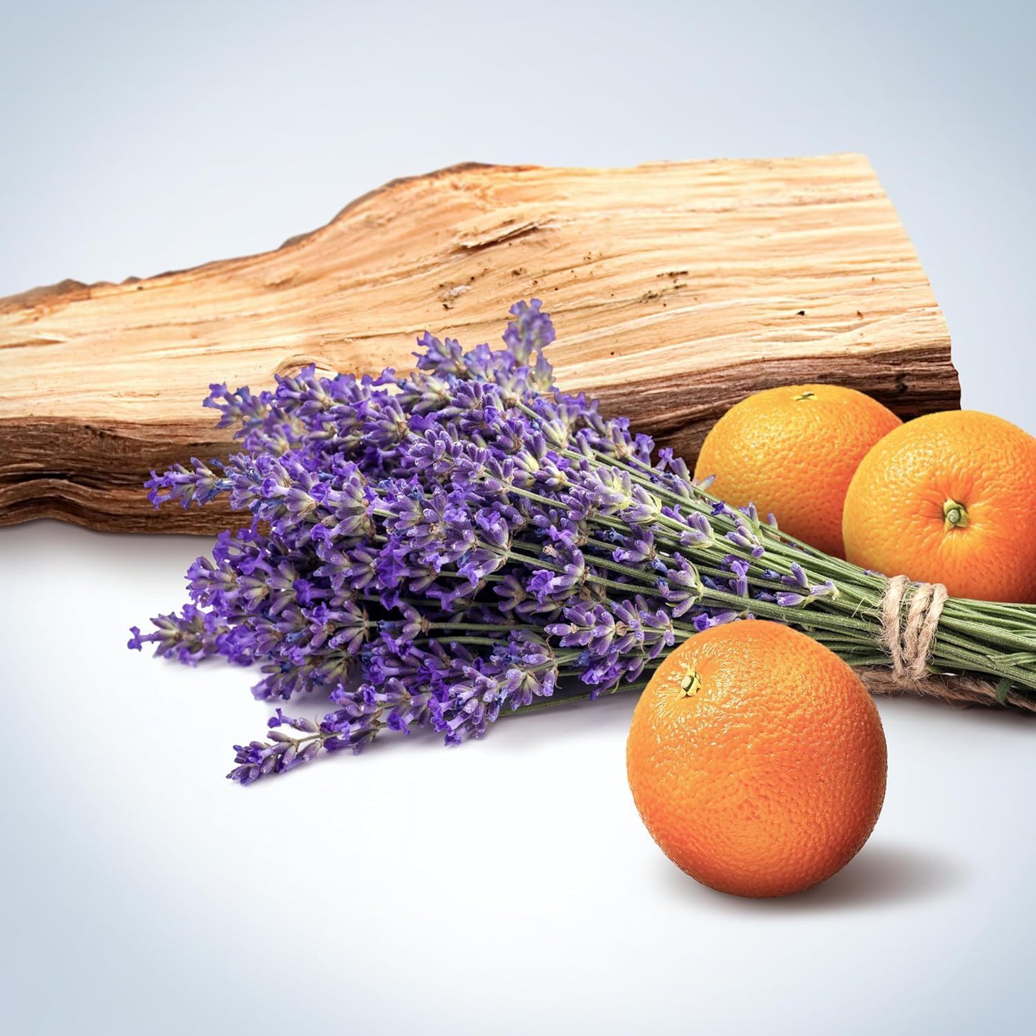 Lavendel, Orangen und Holz. Lavendelstrauß, drei Orangen, Holzstück. Helles, blaues Hintergrundbild.