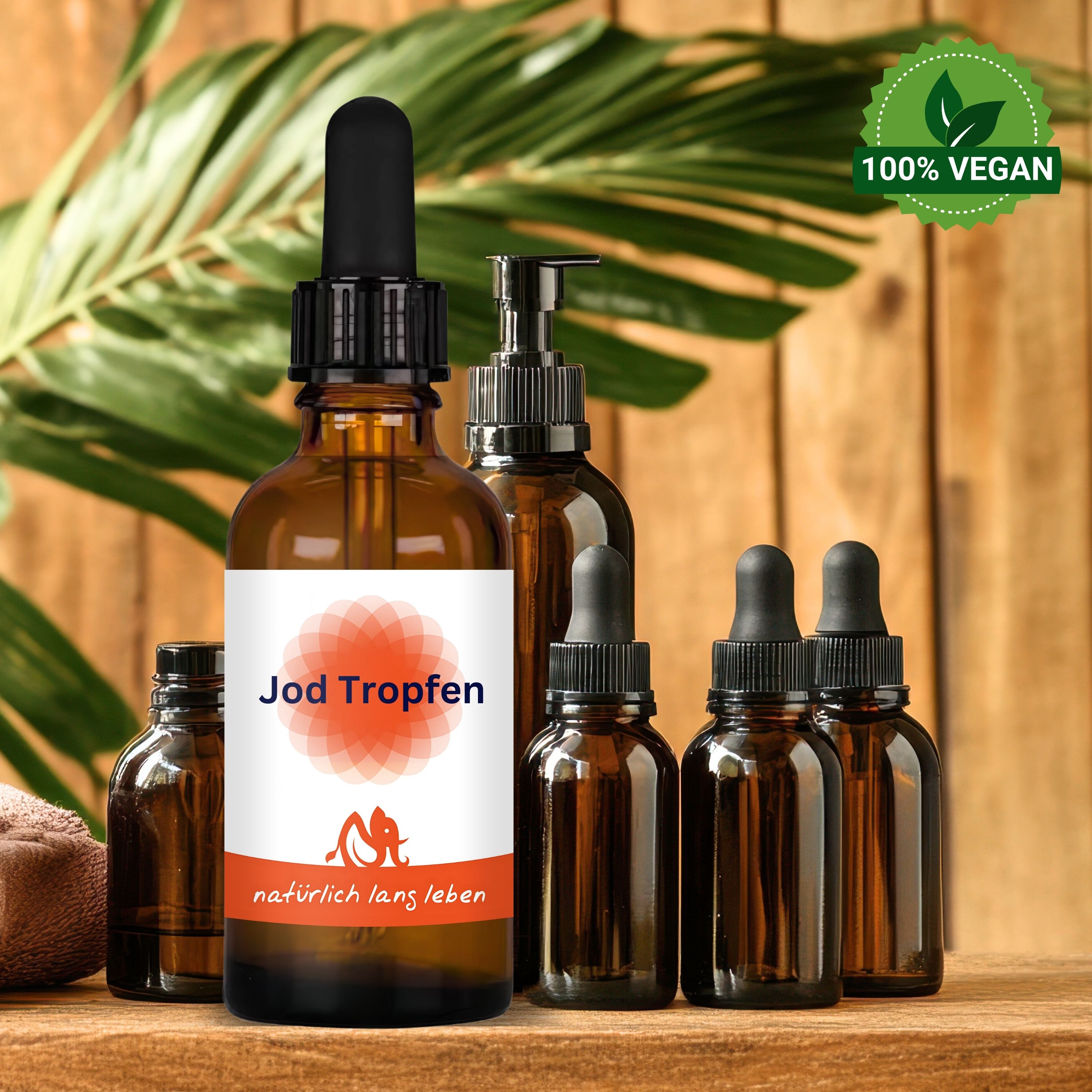 Mehrere braune Glasflaschen mit schwarzen Tropfern. Etikett "Jod Tropfen". Vegan-Siegel. Auf Holzoberfläche, Hintergrund Holz und Blätter.