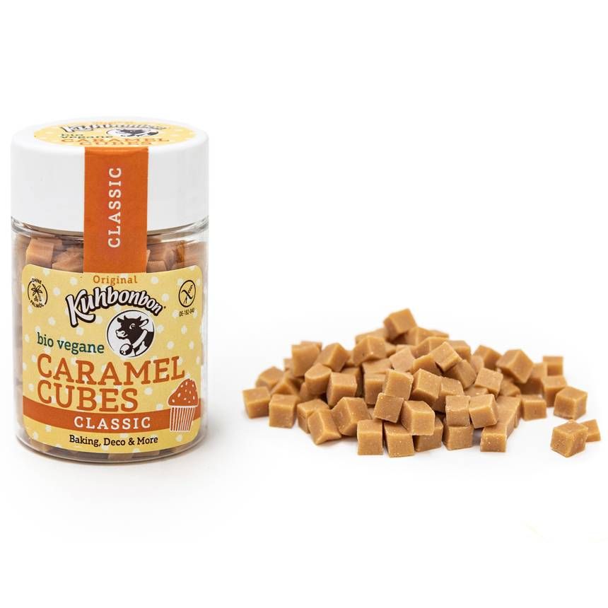 Glas mit Karamellwürfeln und Haufen daneben. Aufschrift: Kuhbonbon Caramel Cubes Classic glutenfrei.