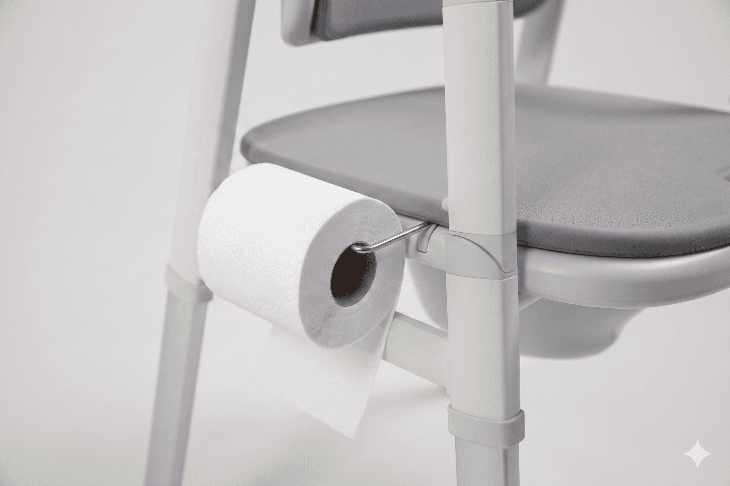 Toilettenstuhl mit Toilettenpapierhalter. Ein Toilettenpapierrolle ist am Stuhl befestigt.