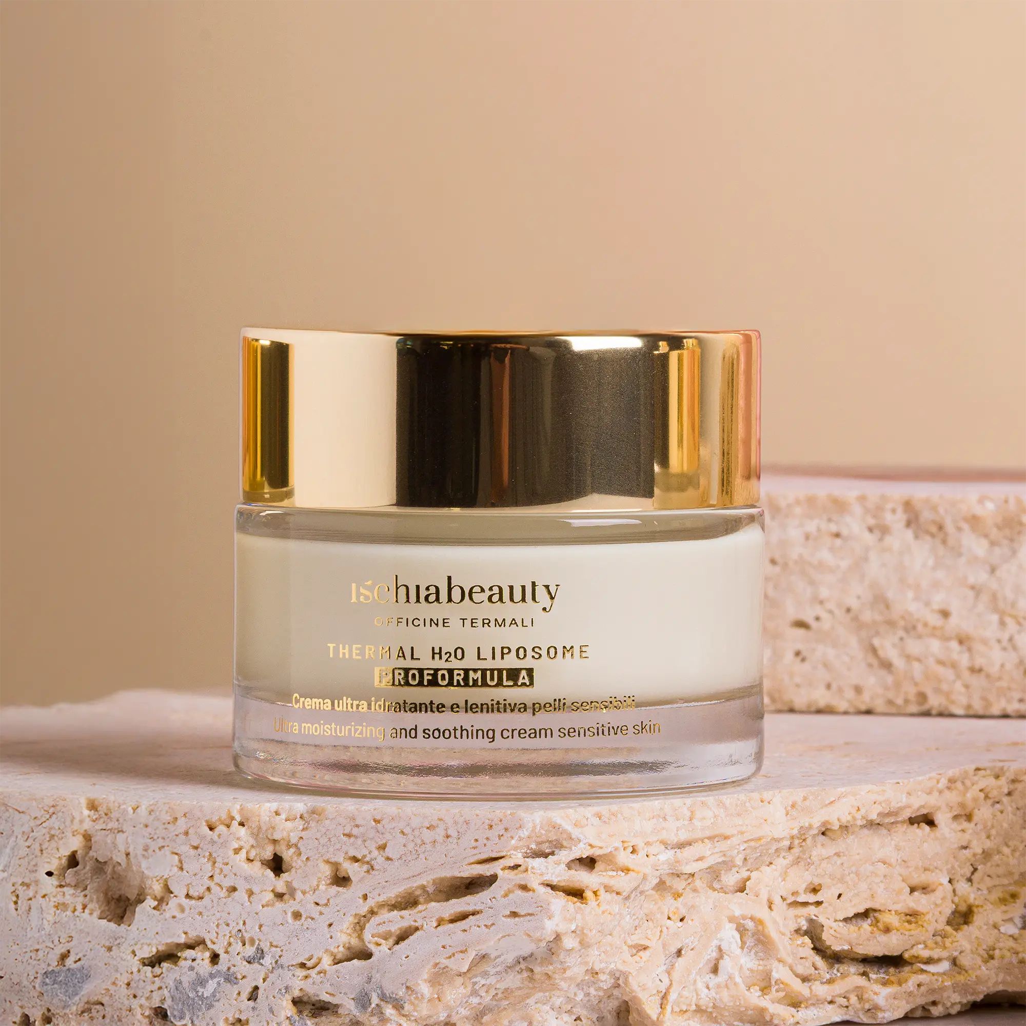 Creme-Behälter mit goldenem Deckel. Text: ischiabeauty, Thermal H2O Liposome, Proformula. Auf Stein platziert.