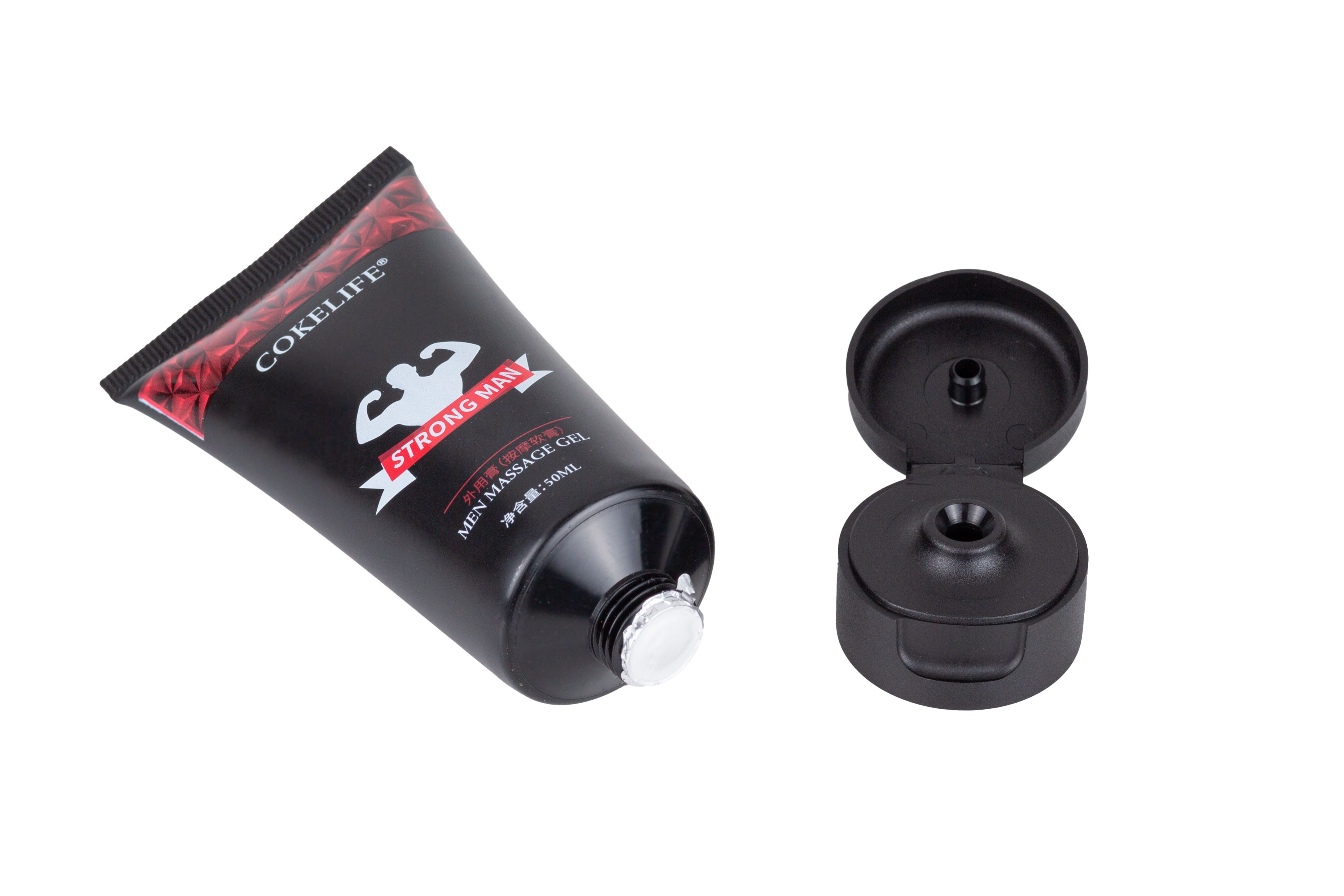 Schwarze Tube mit rotem Muster und Aufschrift. Offener Deckel daneben. Text: COKELIFE, STRONG MAN, MEN MASSAGE GEL.