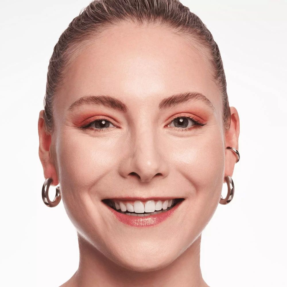 Frau mit orangefarbenem Lidschatten und silbernen Ohrringen.