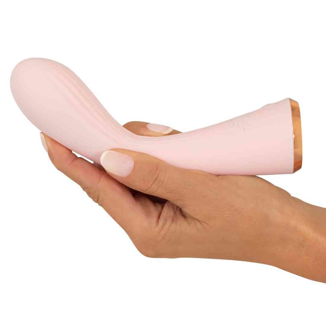 Rosa Vibrator in einer Hand gehalten. Geriffelte Oberfläche, goldfarbener Rand. Kleeblatt-Symbol.