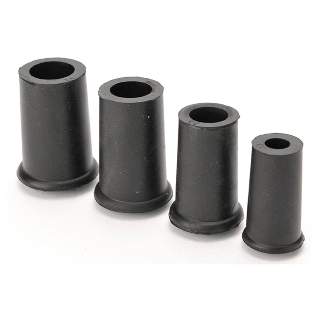 Vier schwarze Gummipuffer. Zylindrische Form mit breitem Boden und Loch in der Mitte. Auf weißem Hintergrund.