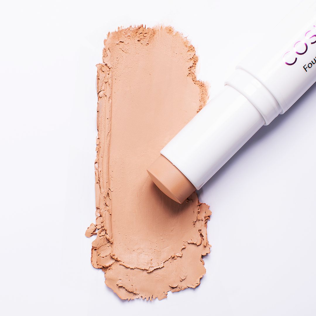 Foundation Stick neben einem beigen Farbfleck. Der Stick ist weiß mit der Aufschrift Cosline Foundation Stick.