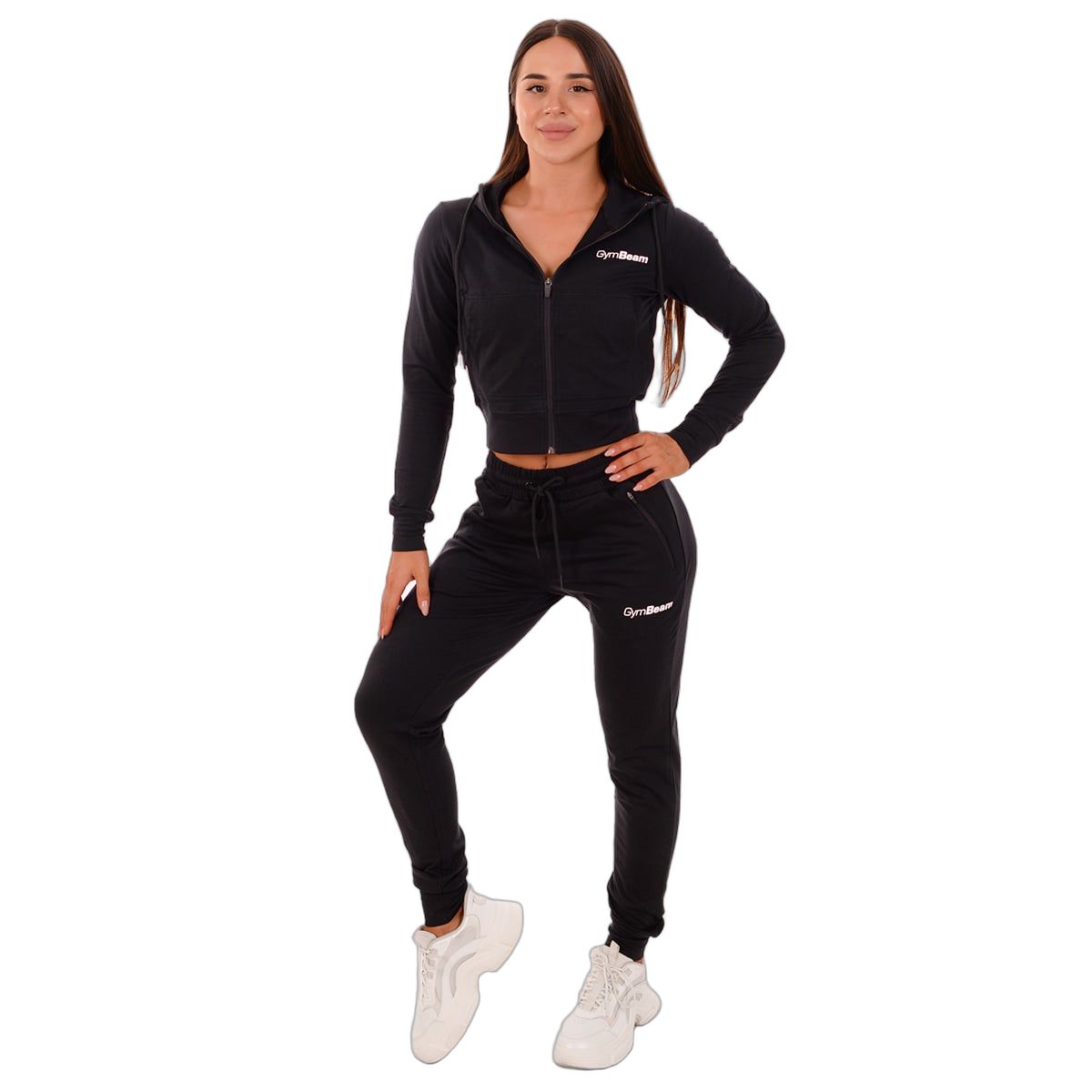 Frau in schwarzer Jogginghose und Kapuzenjacke von GymBeam, mit Kordelzug und Reißverschlusstaschen.