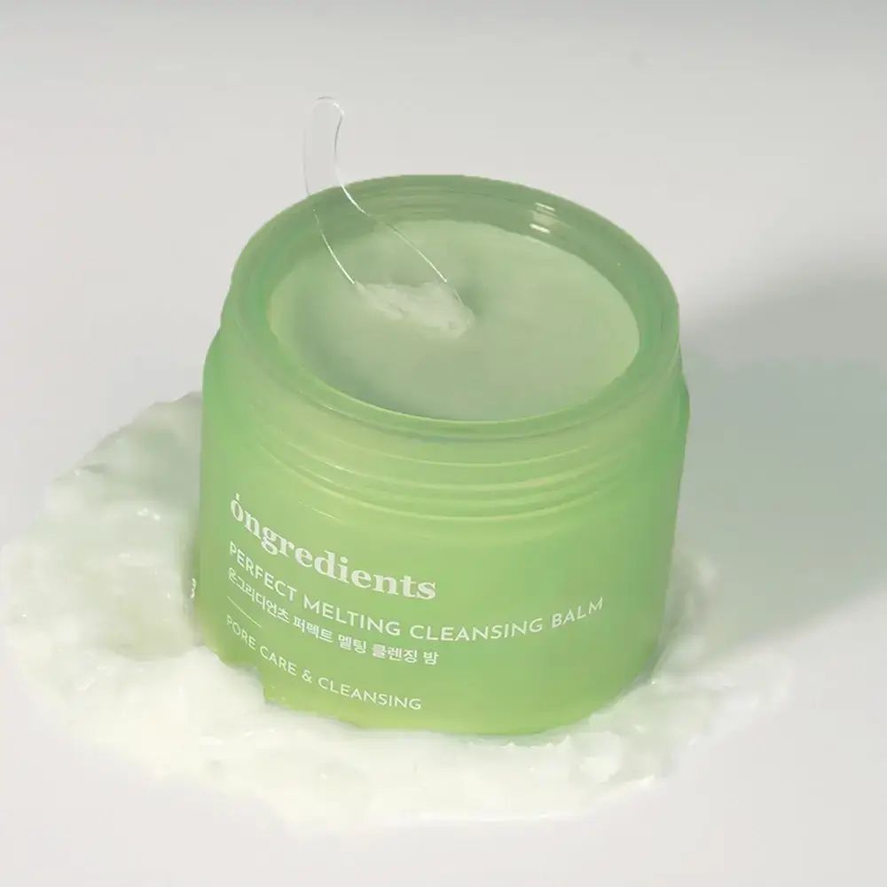 Grünes Glas mit grünem Balsam. Aufschrift: Perfect Melting Cleansing Balm. Ein transparenter Spatel liegt im Balsam. Produkt auf weißem Untergrund.