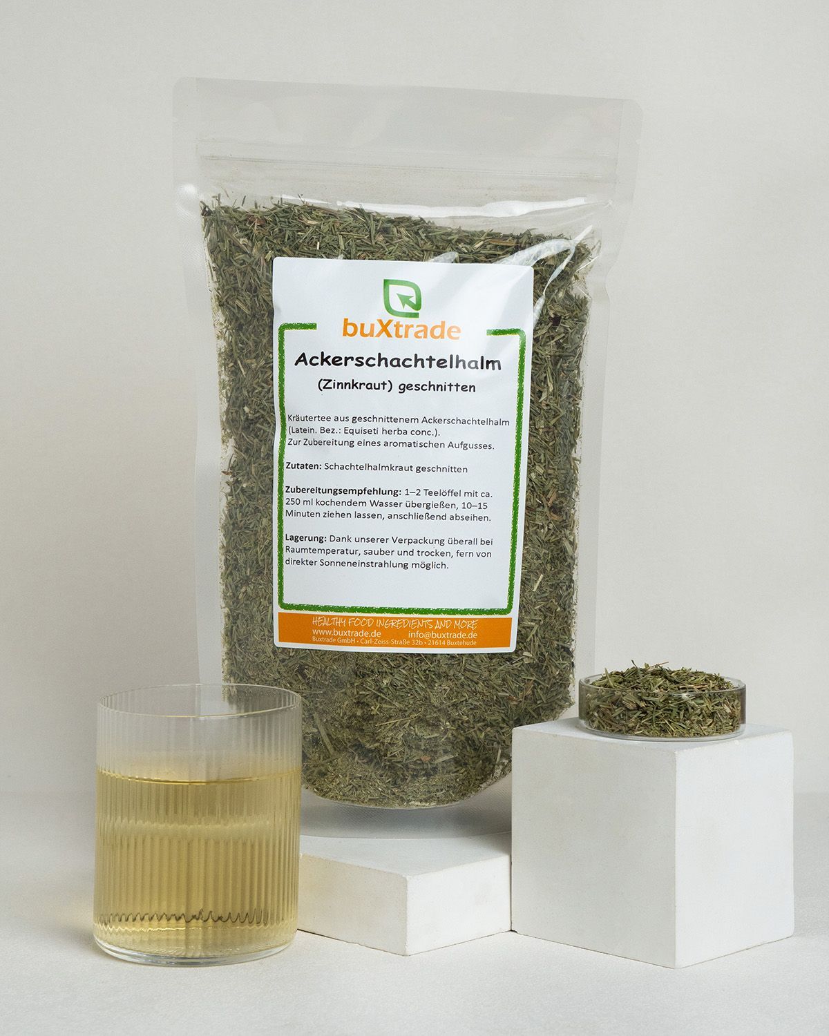 Ackerschachtelhalm-Kraut in Verpackung, Glas mit Tee und kleine Schale mit Kraut.