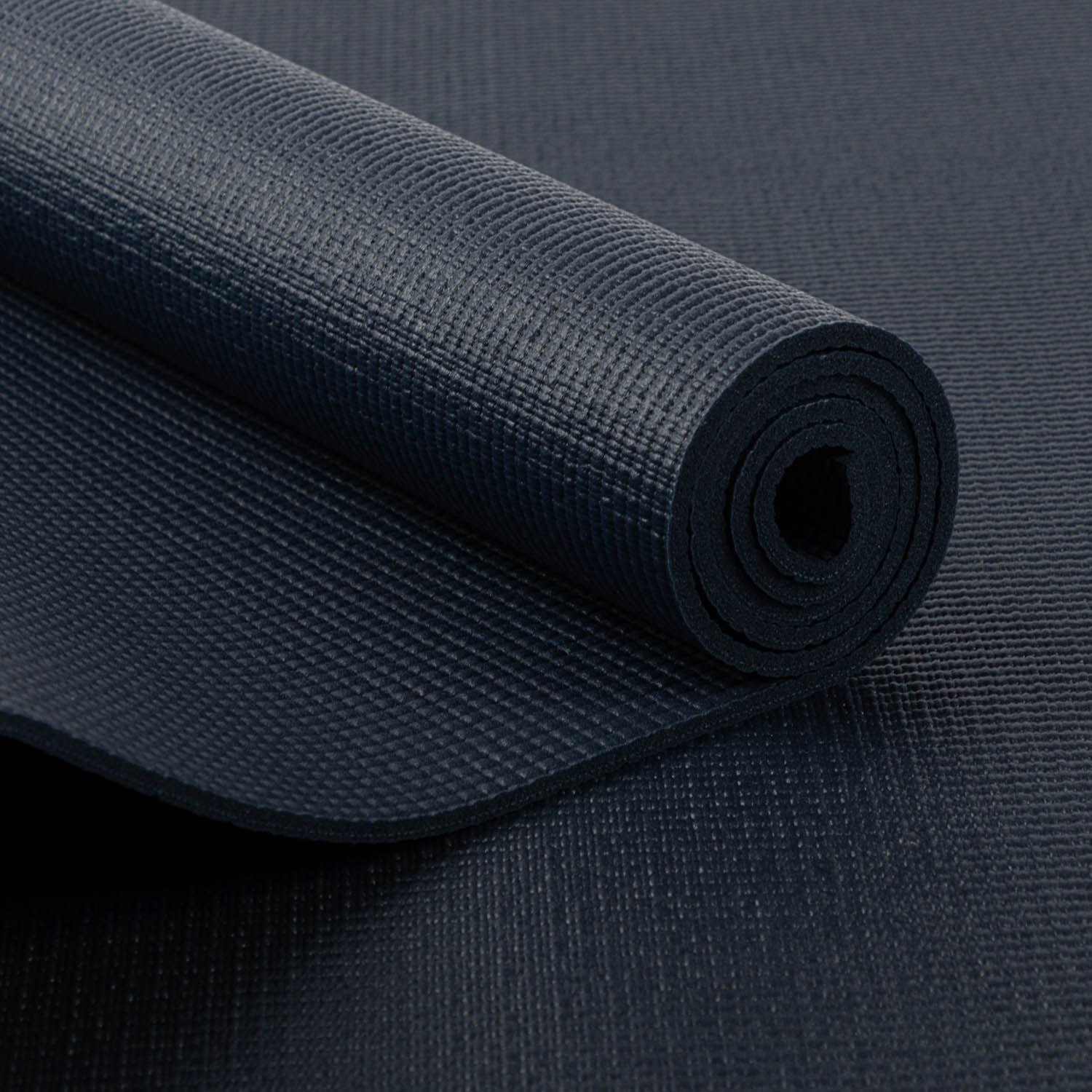 Opgerolde yogamat, donkerblauw. Gestructureerd oppervlak. Gedeeltelijk opgerold, toont de binnenkant.