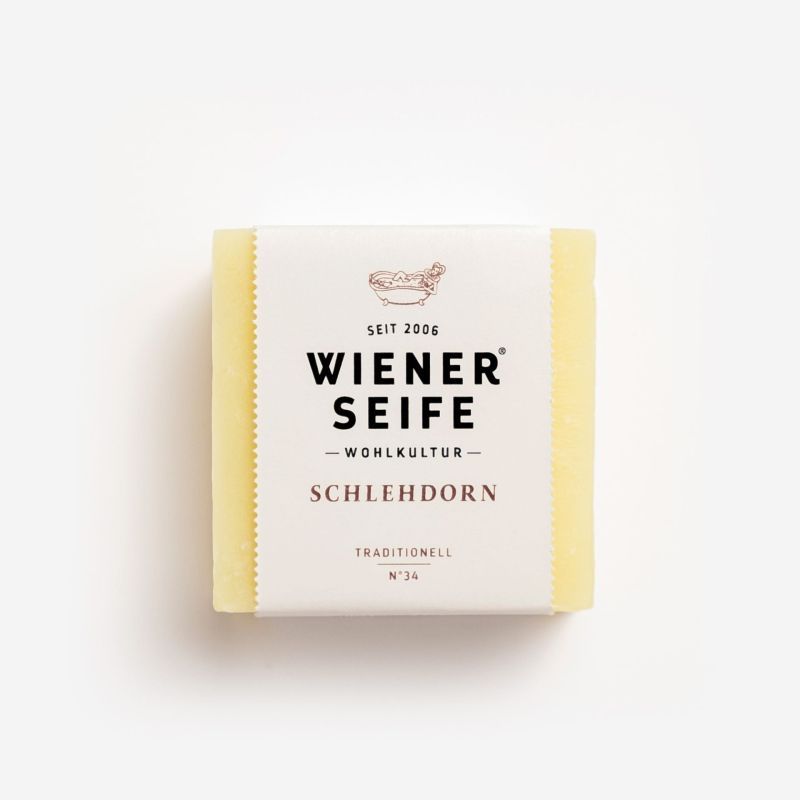 Seife mit Papierbanderole. Aufschrift: Wiener Seife, Schlehdorn, Traditionell N°34. Logo mit Tier. Gelbliche Seife.