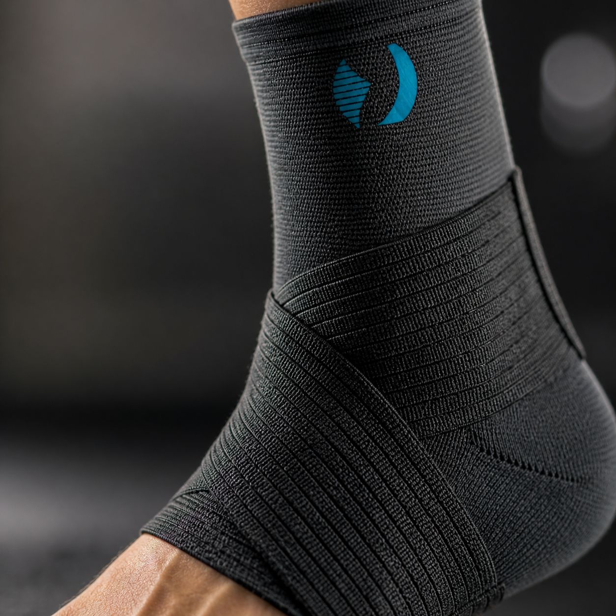 Nahaufnahme einer schwarzen Sprunggelenkbandage mit blauem Logo. Gewebtes Material mit Bandagen.
