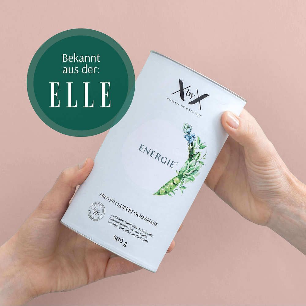 Produkt-Behälter 'XbyX Energie', gehalten in Händen. 'Bekannt aus: ELLE'. 'Protein Superfood Shake'.
