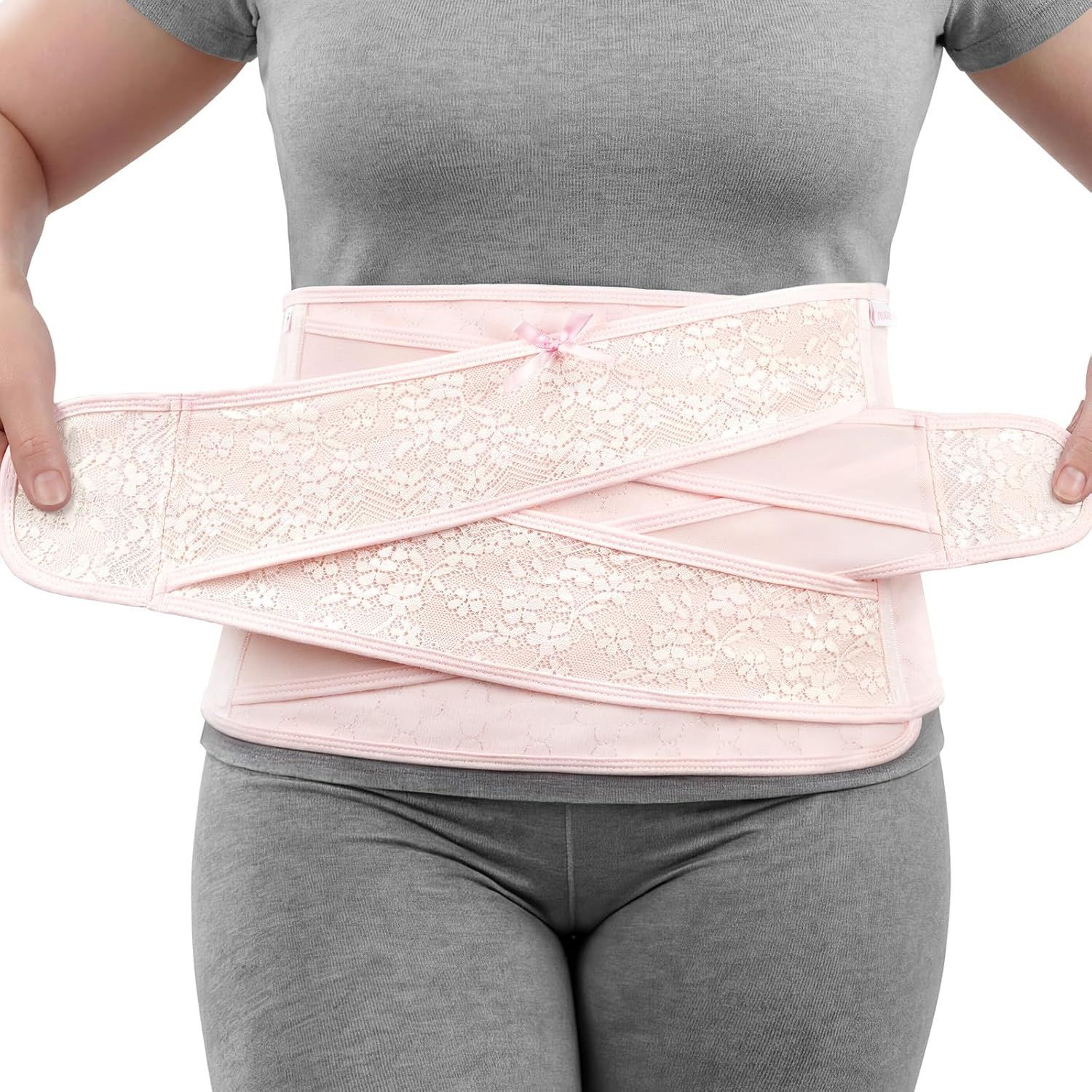 Frau mit Baby, trägt einen rosa Bauchwickel mit V-förmiger Kreuzunterstützung.