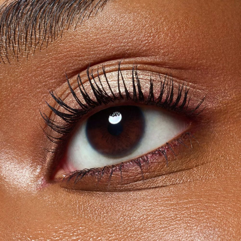 Nahaufnahme eines Auges mit aufgetragenem Lidschatten. Dunkle Wimpern.