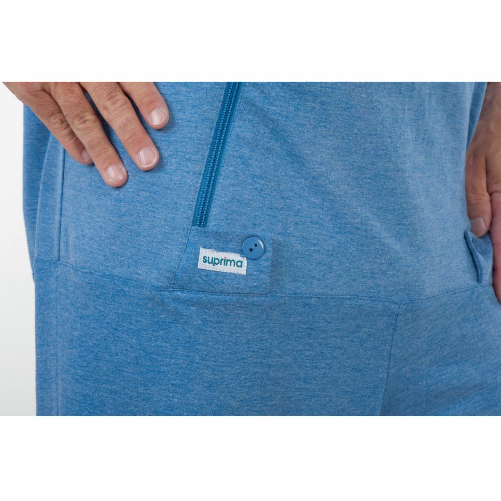 Detailaufnahme des Pflegeoveralls. Blaue Farbe, Reißverschluss, Knopf und Etikett mit "suprima".