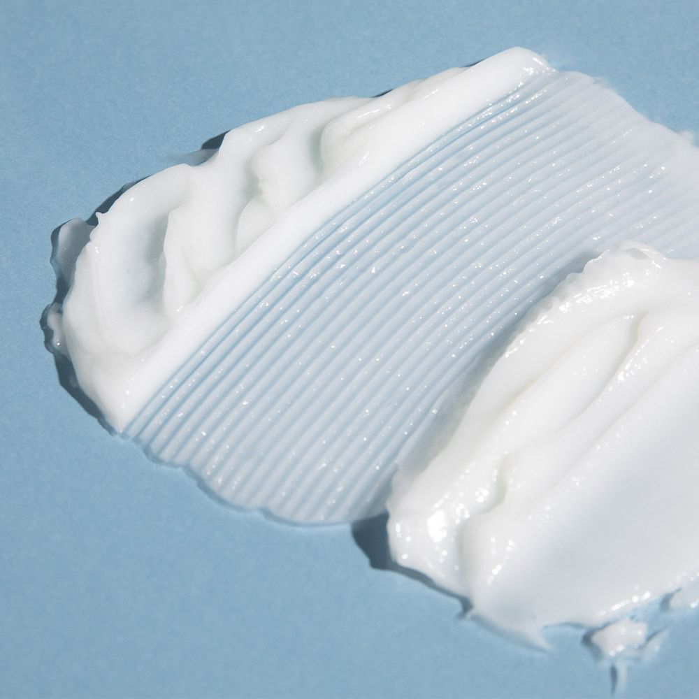 Nahaufnahme von weißer Creme auf blauem Hintergrund. Creme mit geriffelter und glatter Textur.