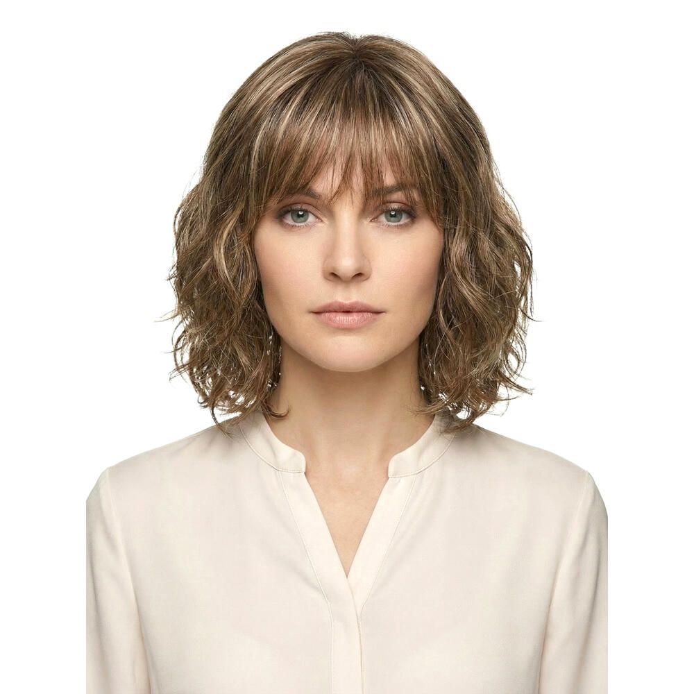 Perücke mit gewelltem, schulterlangem Haar und Pony. Gezeigt an einer Frau vor weißem Hintergrund.