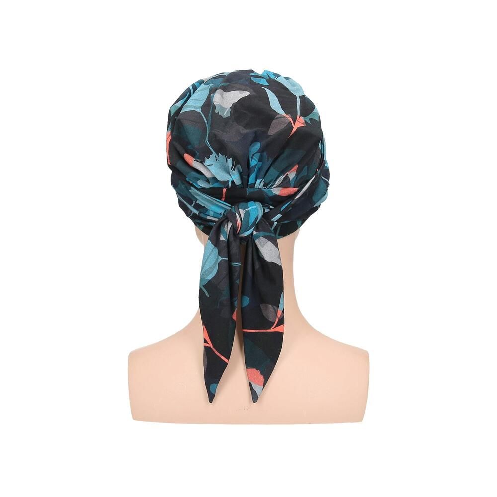 Turban Letti, floral bedruckt, auf einer Büste. Farben: Schwarz, Türkis, Rosa. Stoff mit Falten. Rückansicht mit Schleife.