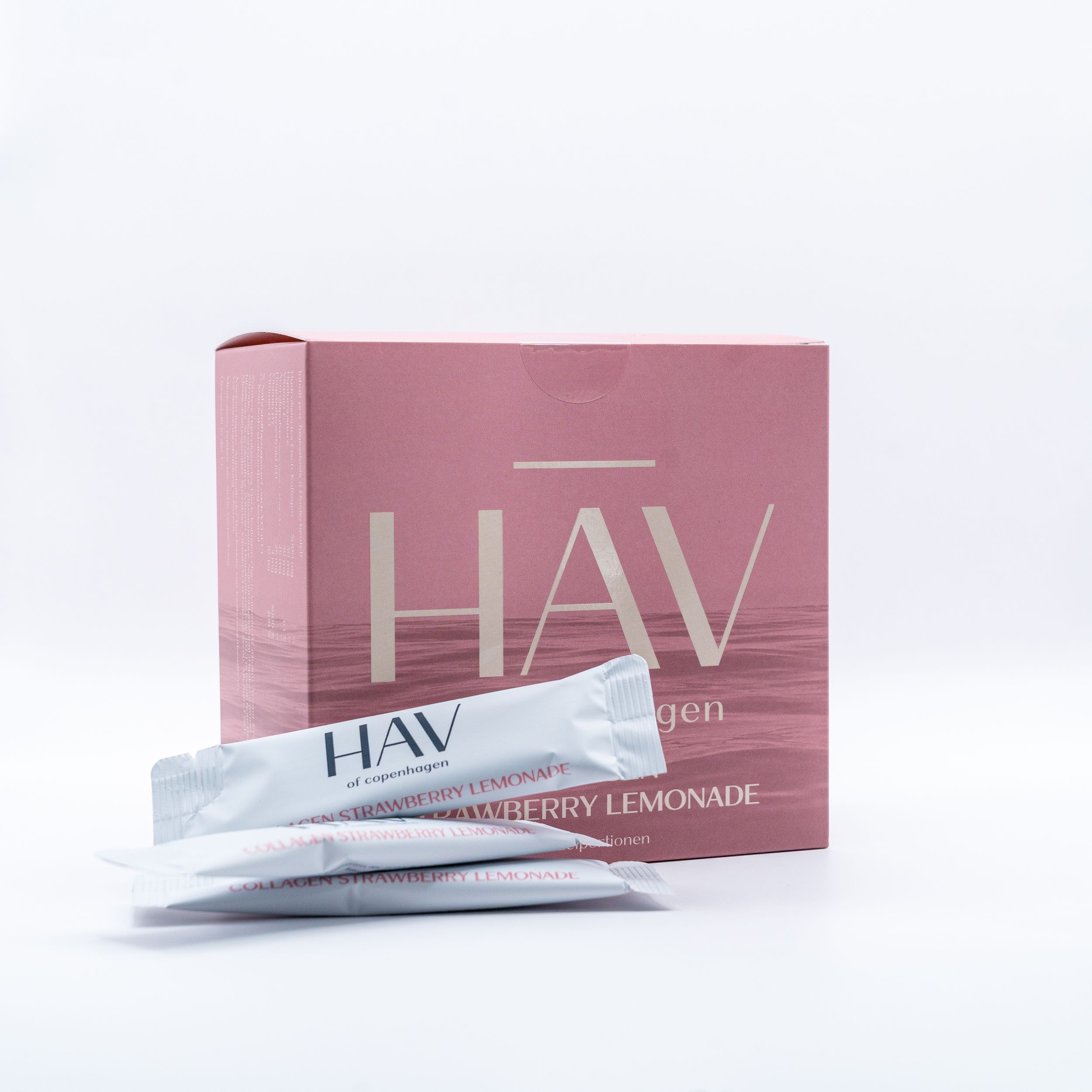 Rosa Karton mit HAV Collagen Strawberry Lemonade Schriftzug. Zwei Beutel daneben.