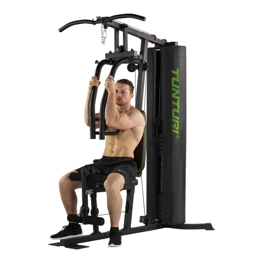 Mann trainiert an Tunturi Home Gym HG20. Brustpresse-Übung. Schwarze Station, grüne Akzente, Gewichtsblock.