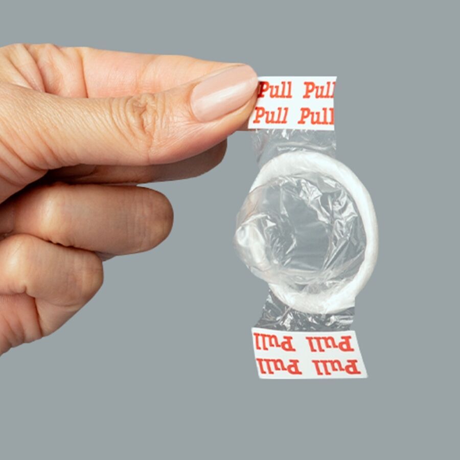 Geöffnetes Kondom, gehalten von einer Hand. Der Streifen zum Öffnen ist sichtbar.