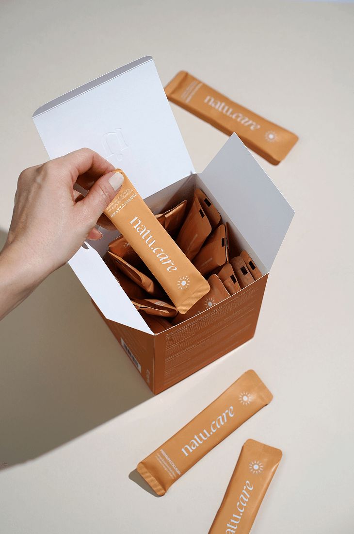 Geöffnete Produktbox mit einzelnen Beuteln. Eine Hand greift nach einem Beutel. Beutel mit Sonnenlogo.