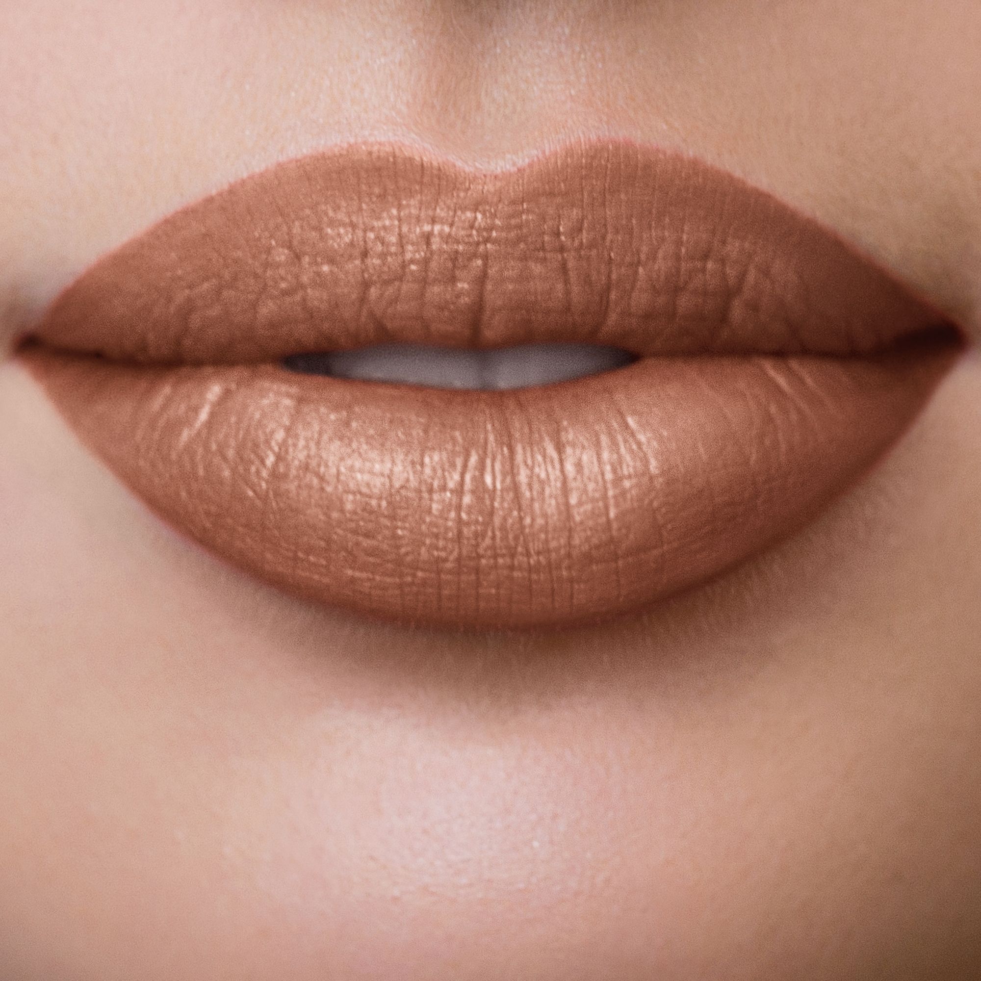 Nahaufnahme von Lippen, bedeckt mit Nude-Toffee-Lippenstift. Glänzendes Finish.